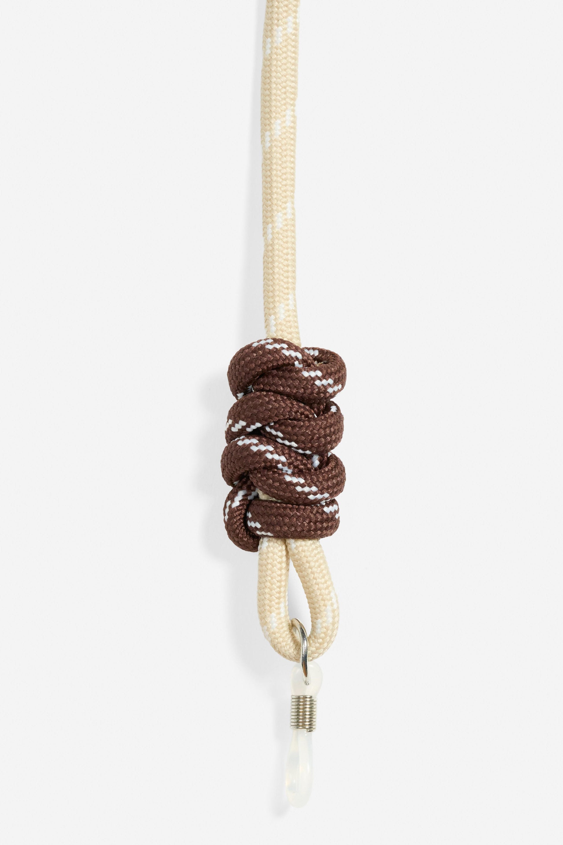 Brown knot on a beige glasses cord against a white background