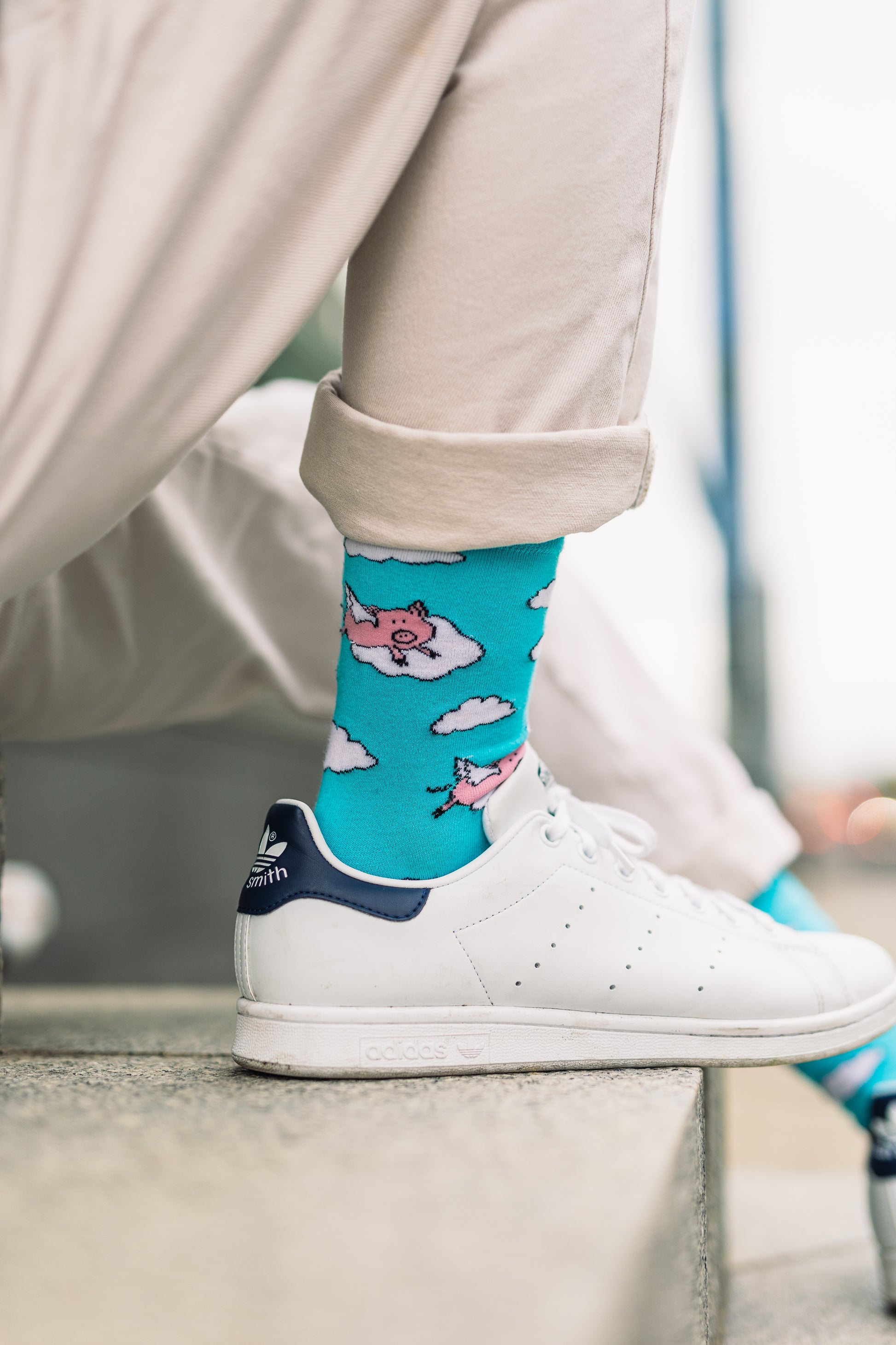 Man wearing blue socks with pigs design and white trainers