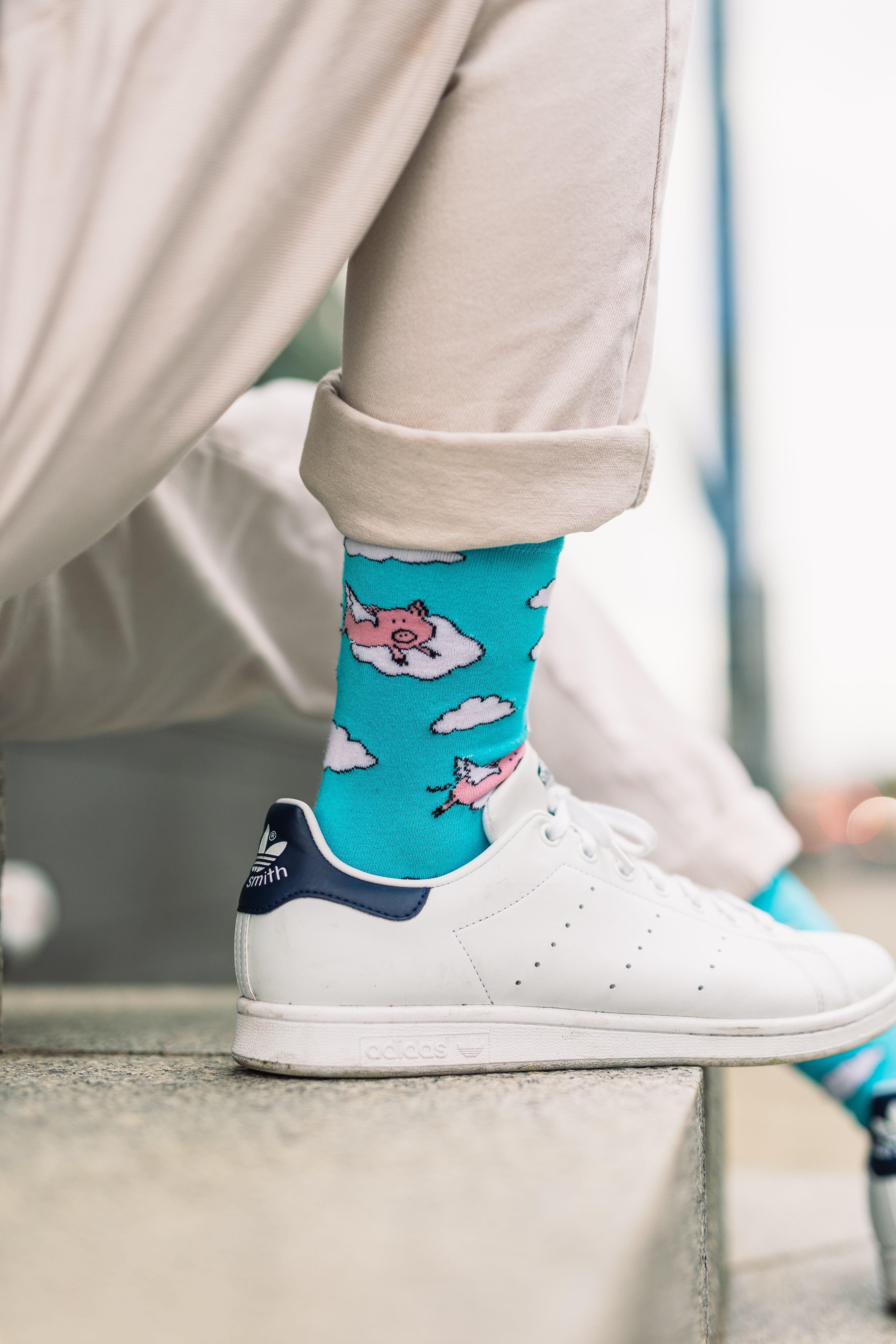 Man wearing blue socks with pigs design and white trainers
