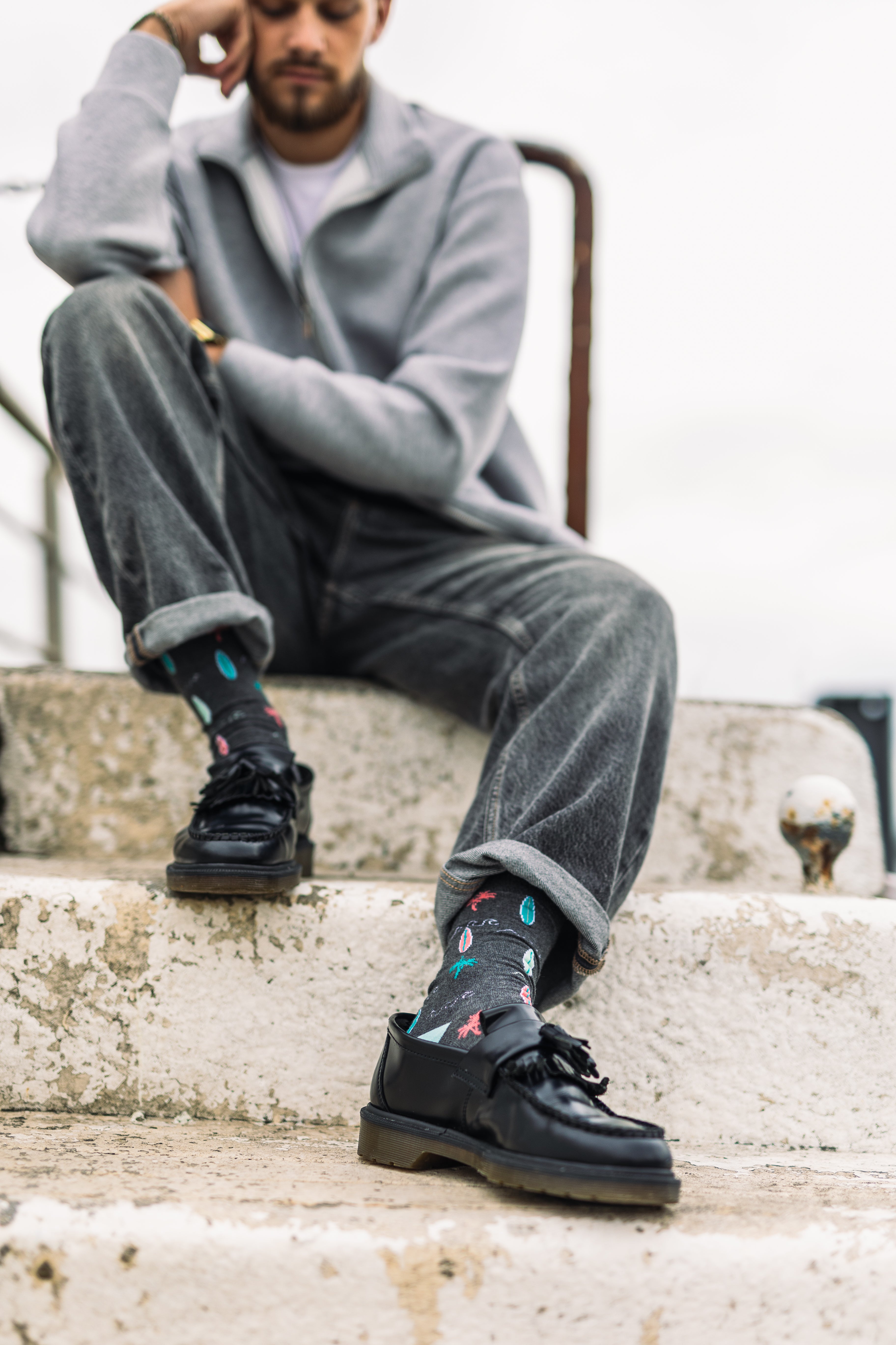 Person wearing black boots and colourful bamboo socks sitting on a stone step.