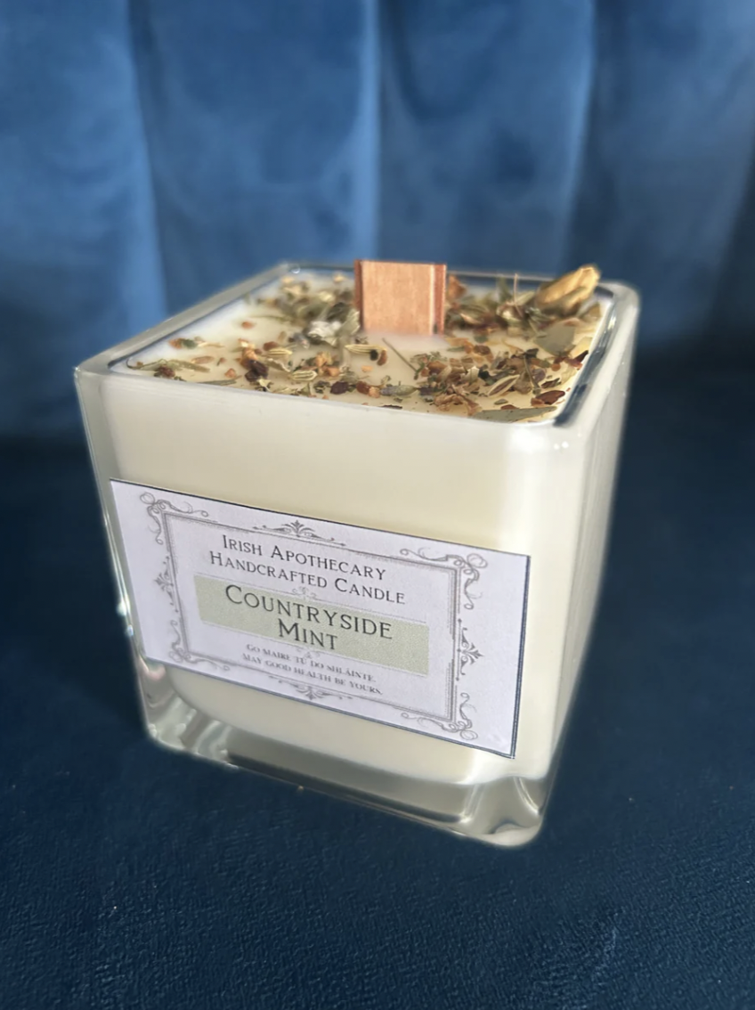 Irish handmade candle in a glass container with a label on a blue background