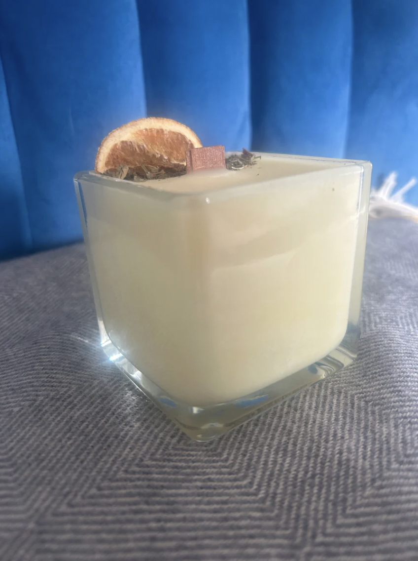 Irish handmade candle in a glass container with decorative elements on a textured surface and blue background