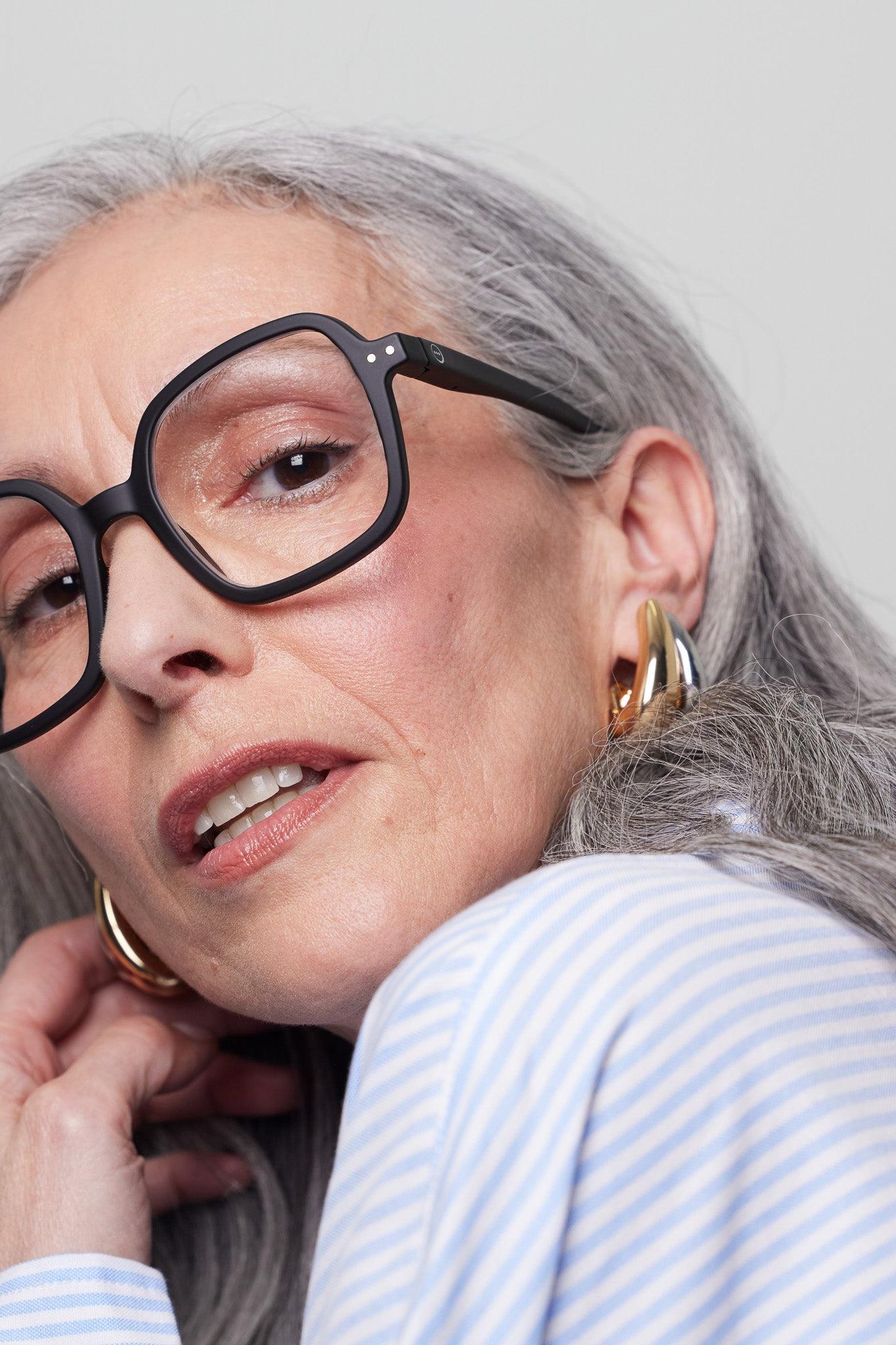 Model wearing the Izipizi Reading #OFFICE Black glasses, showcasing their oversized shape and matte design.