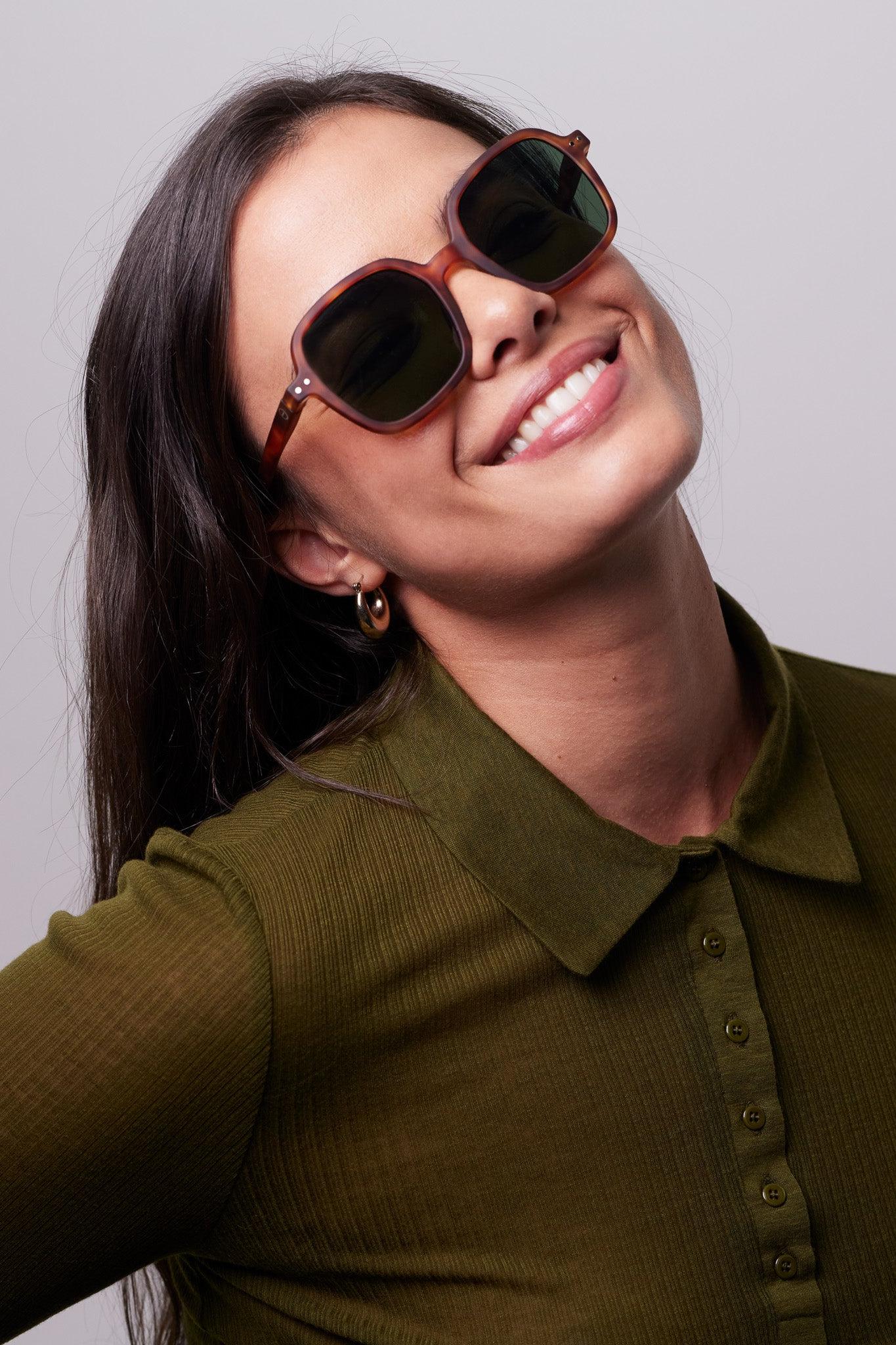 Model smiling wearing the IZIPIZI Sun #OFFICE Havane sunglasses, highlighting their large square design.