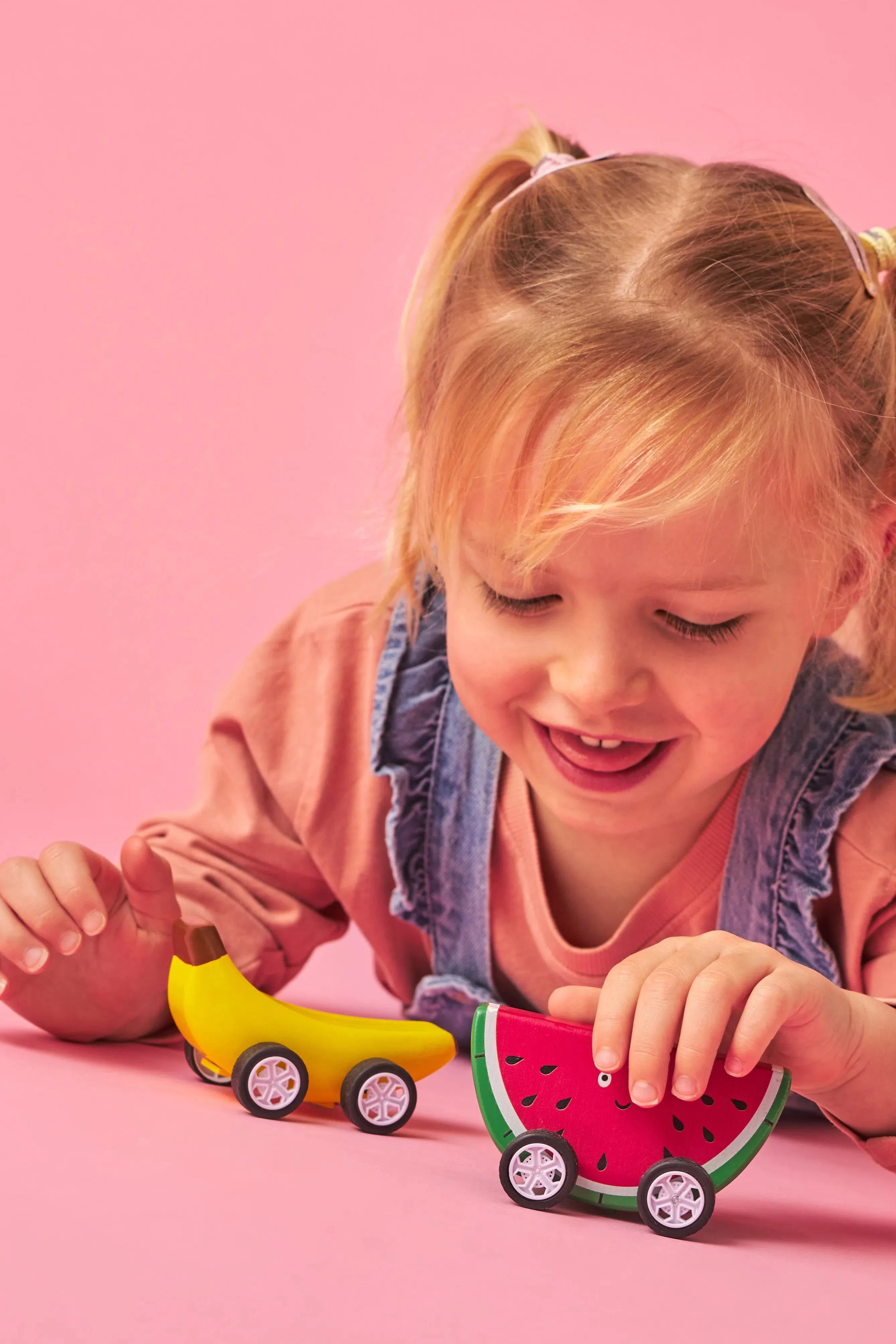 Child playing with kikkerland banana and watermelon fruit fun pullback car.