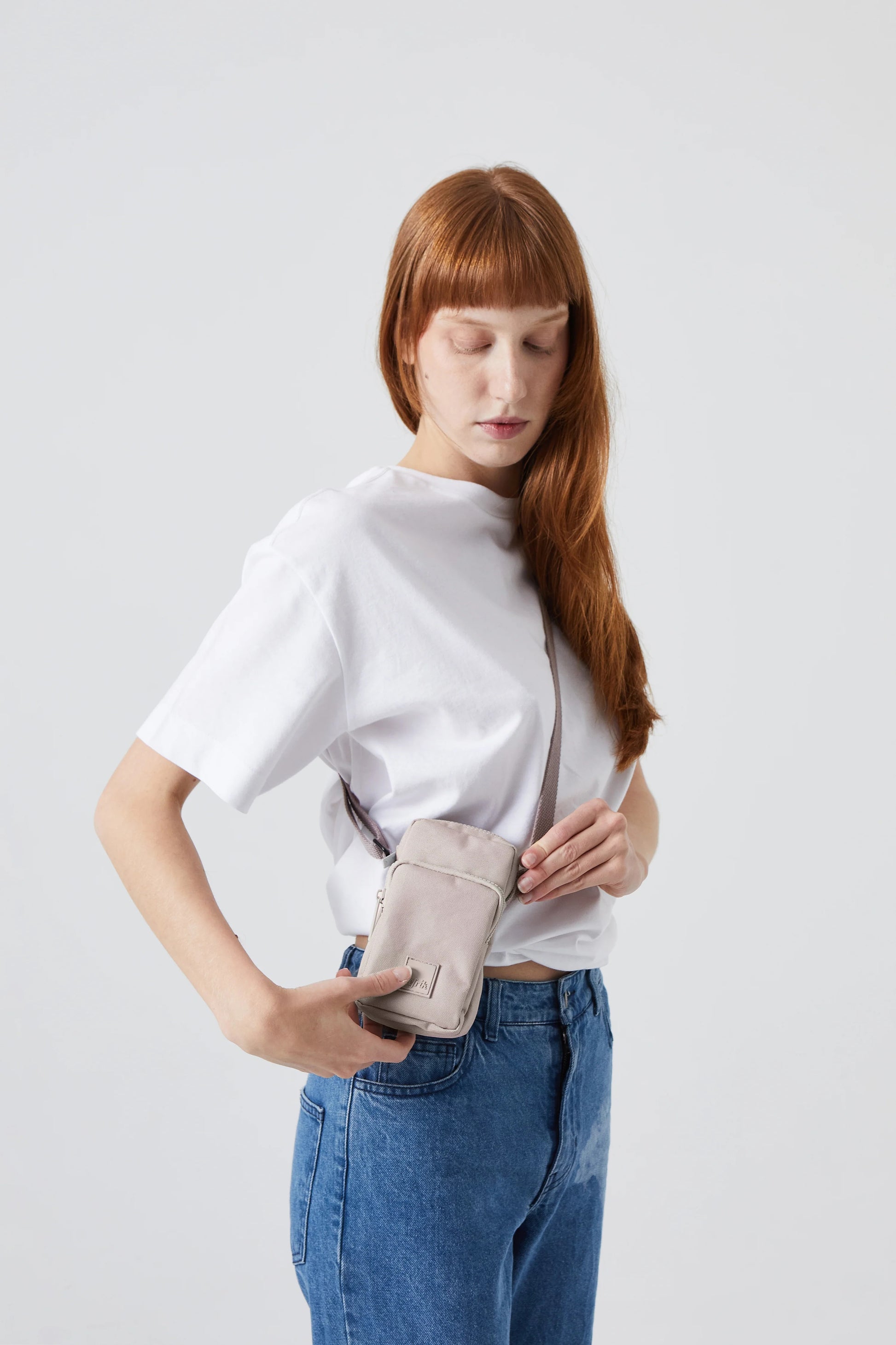Model wearing Lefrik Amsterdam Bag in Ash, a compact rectangular shoulder bag with two compartments, featuring a zip closure and adjustable cotton strap.