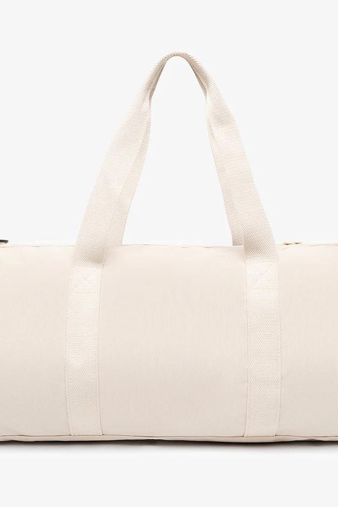 Side view of cream duffle bag with straps.