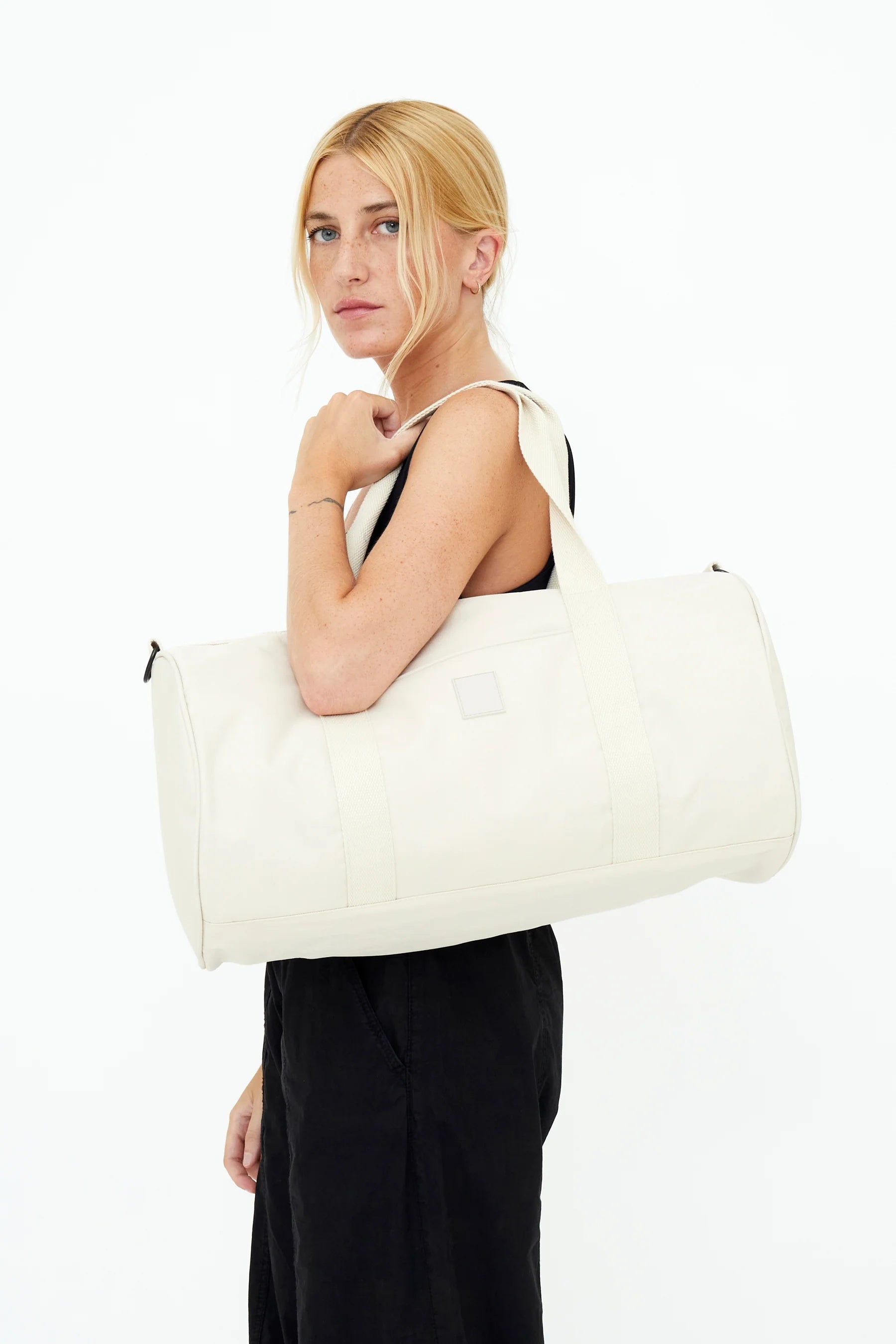 Model carrying the Lefrik Getaway Bag in Ecru over the shoulder, demonstrating its size.