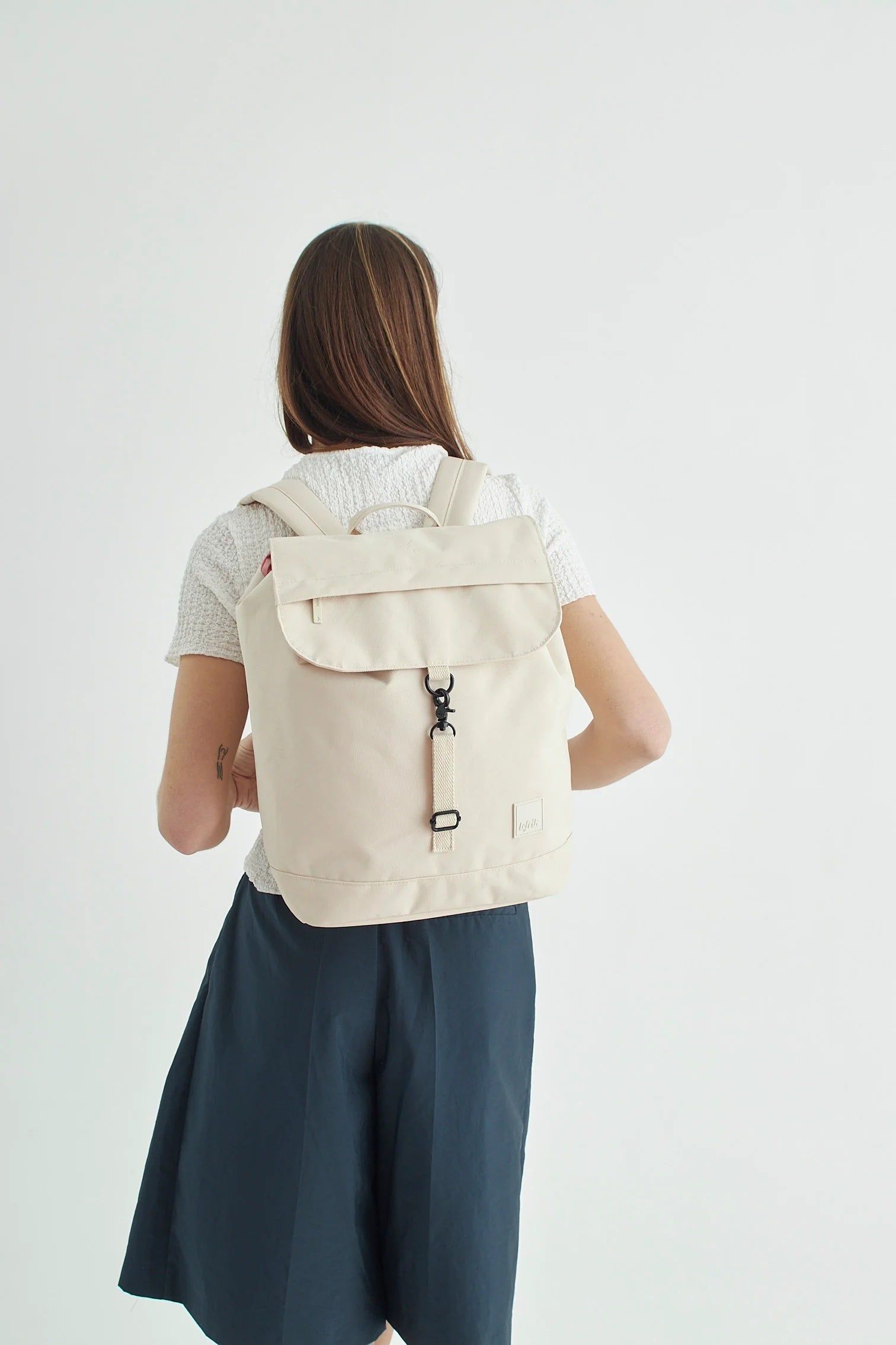 Model wearing the Lefrik Scout Backpack in Ecru Stripes, demonstrating its size and style.