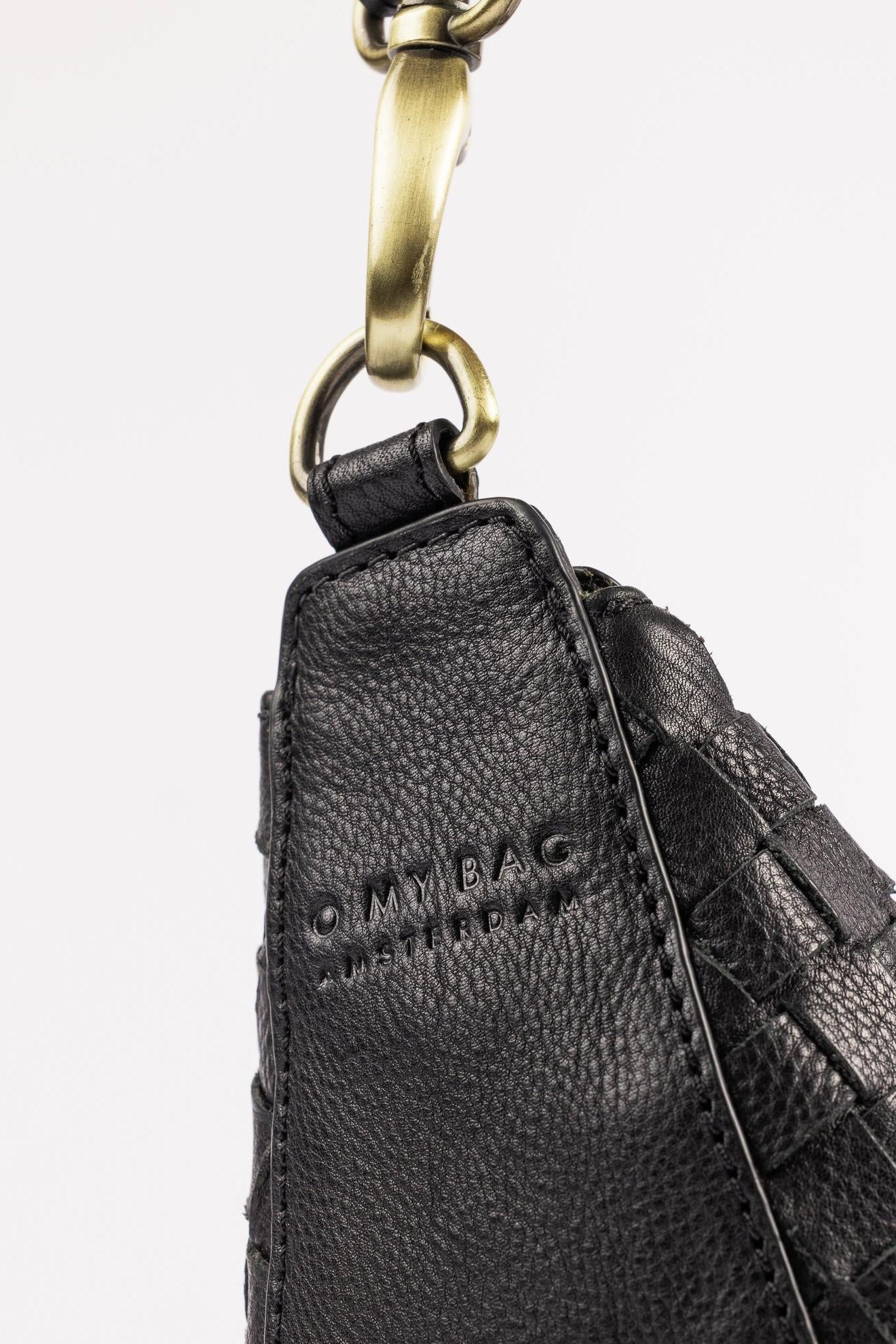 Close-up of a black leather bag with a gold clasp on a white background