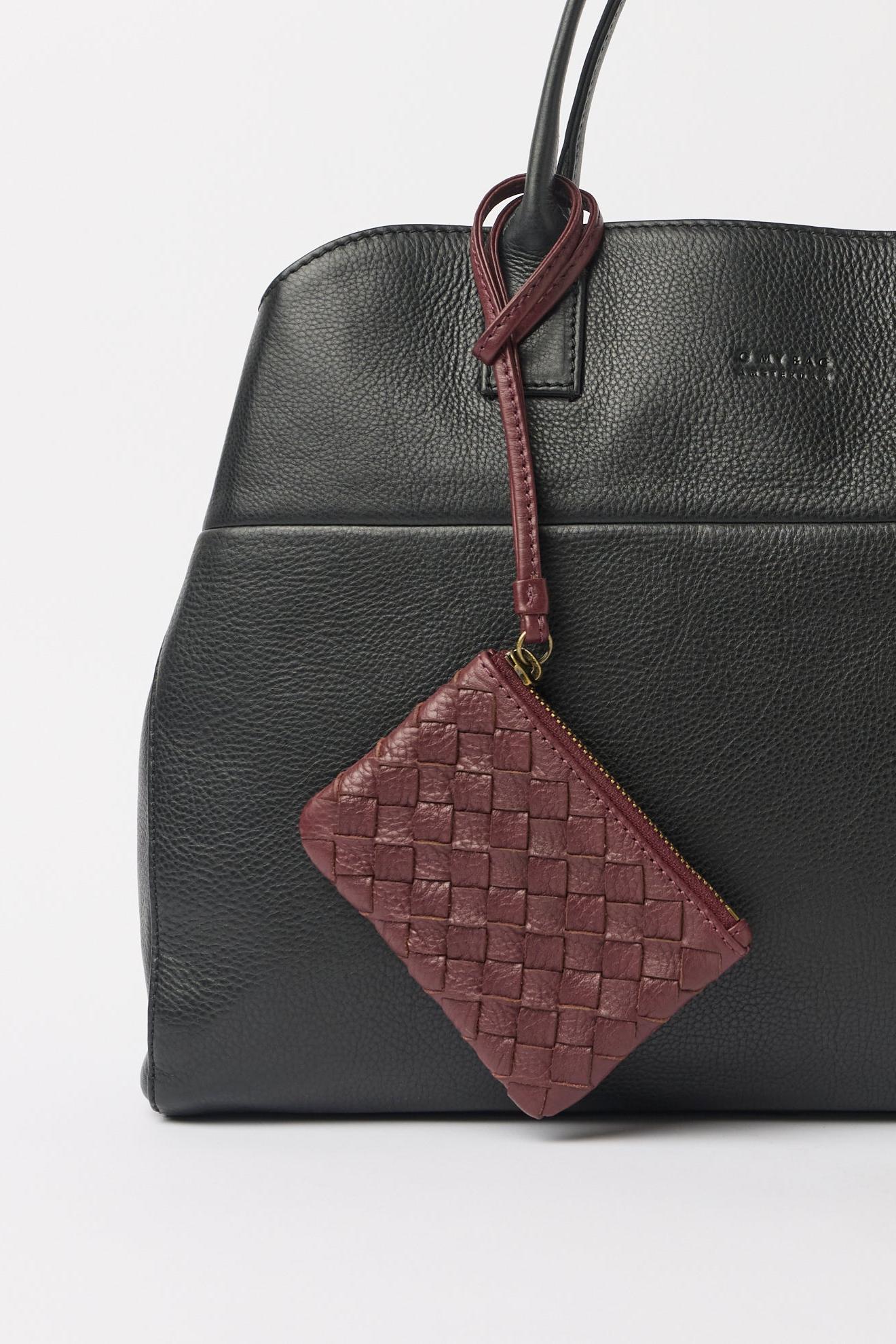 Black leather handbag with a woven brown patch on a white background