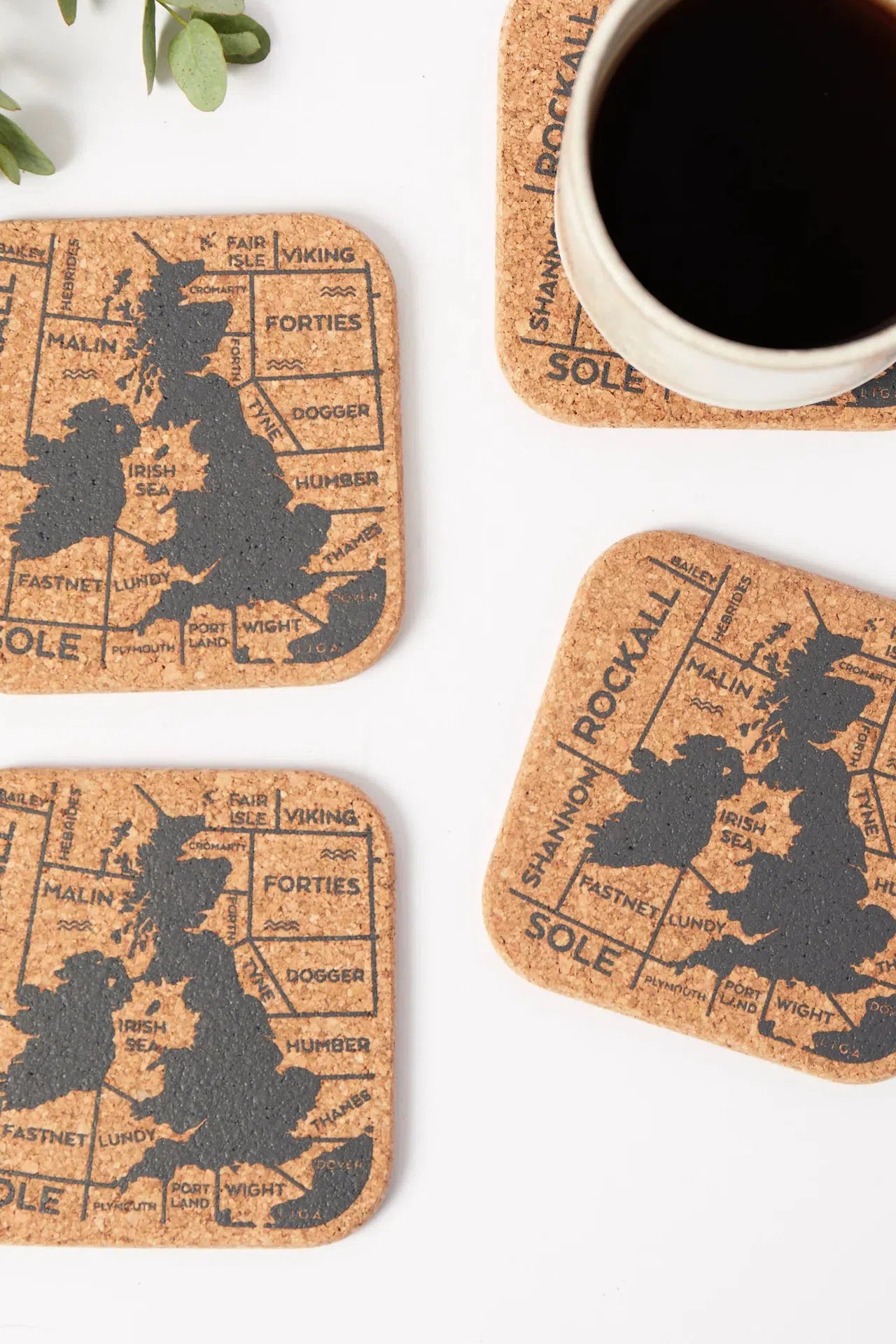 Liga Organic Cork Coasters featuring the Shipping Forecast design on a table with one beneath a teacup.