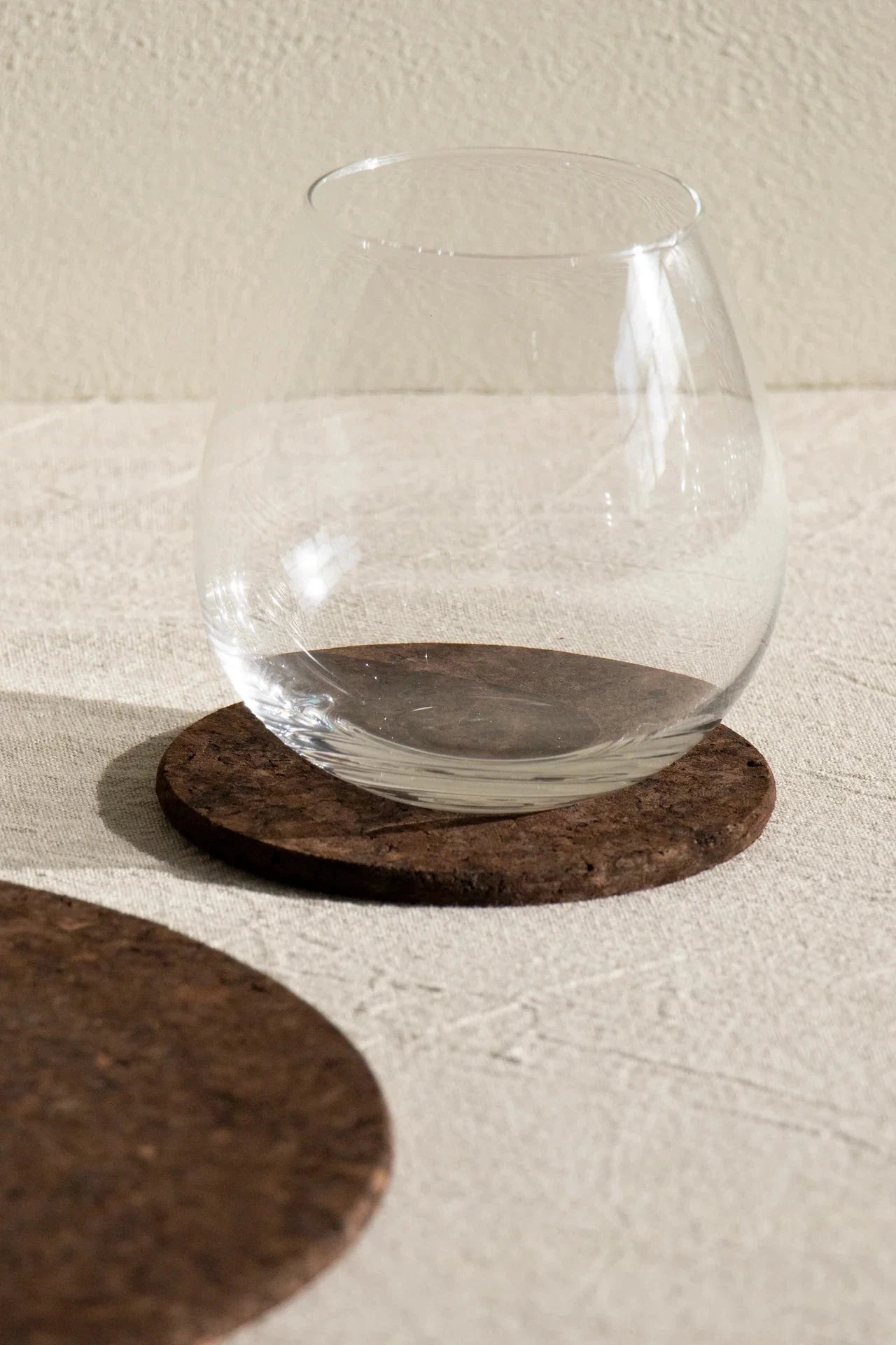 Liga Smoked Cork Round Coaster in use on a dining table.