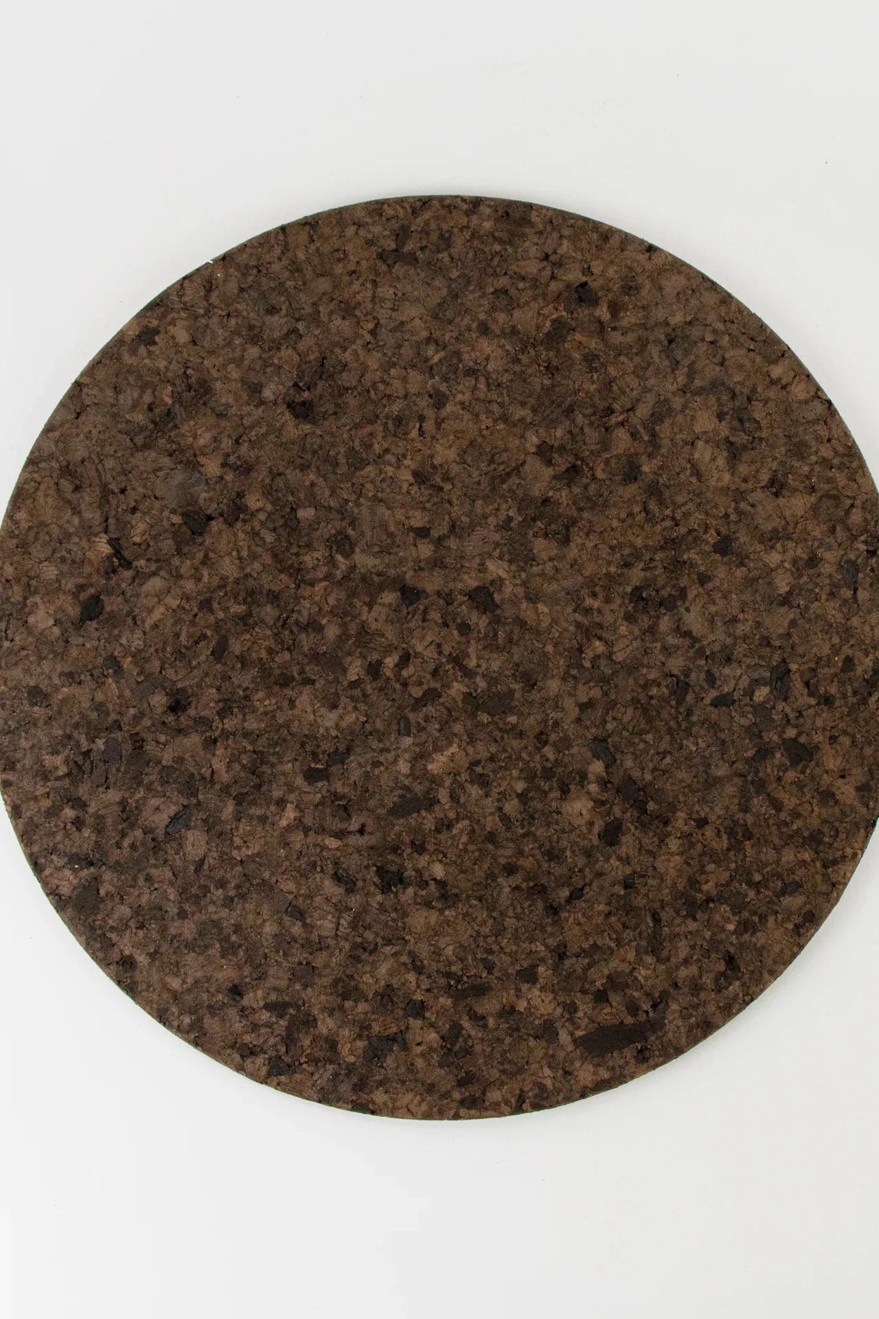 Top view of Liga Smoked Cork Round Placemat on white background.