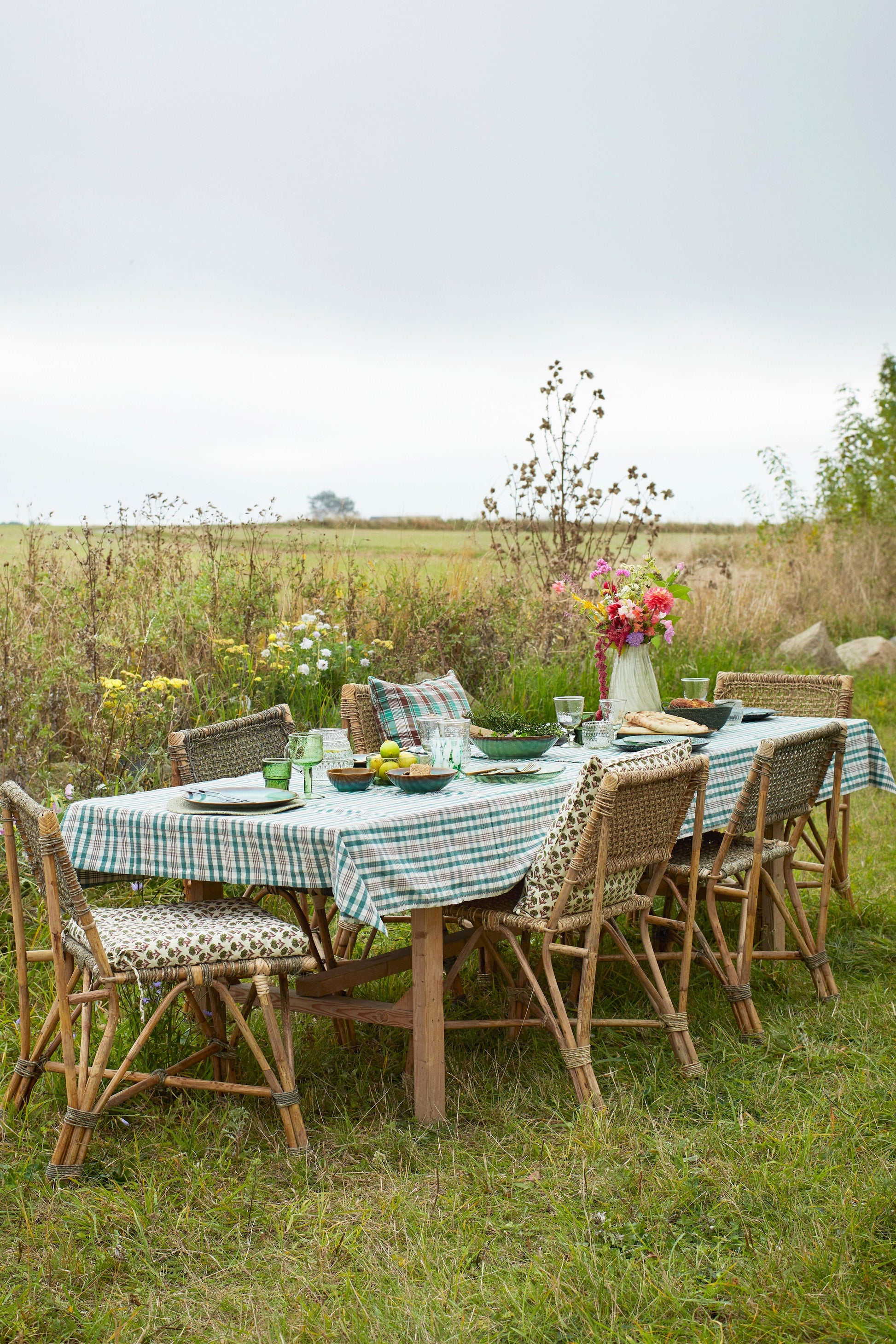 Outdoor dining setup with a table and chairs in a field