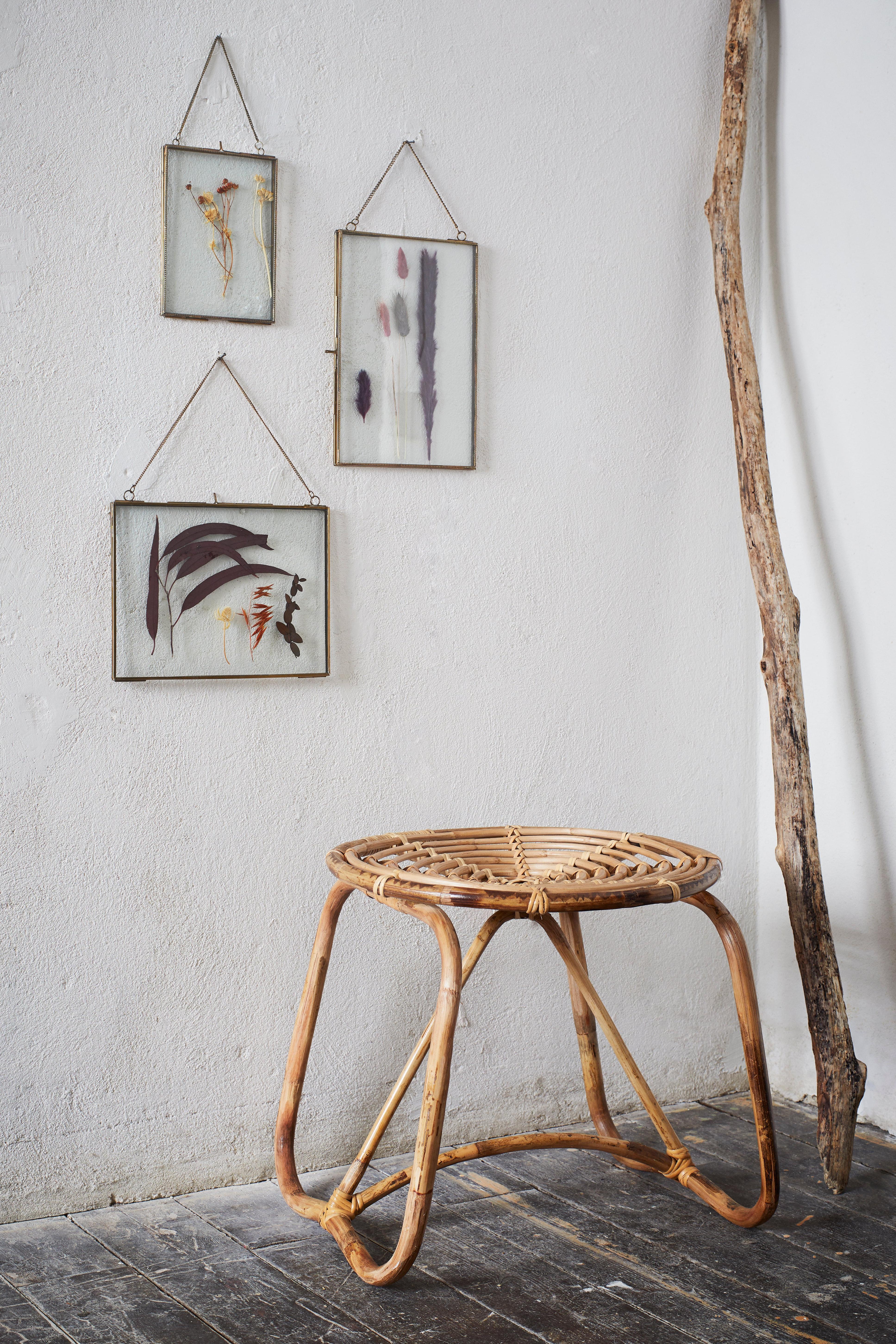 Wicker side table with framed abstract art on a white wall