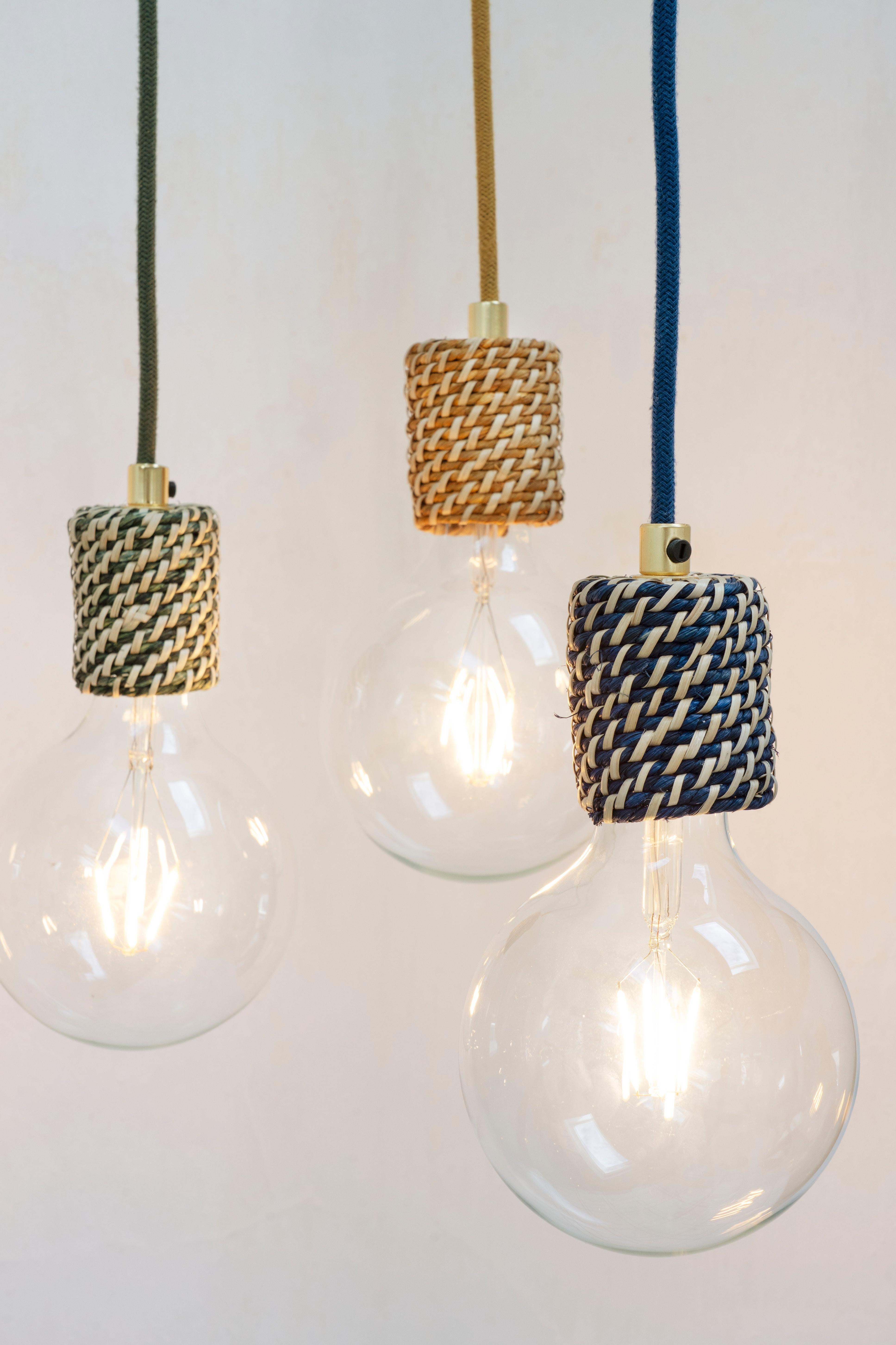 Three light bulbs with woven Madam Stoltz covers hanging against a white background