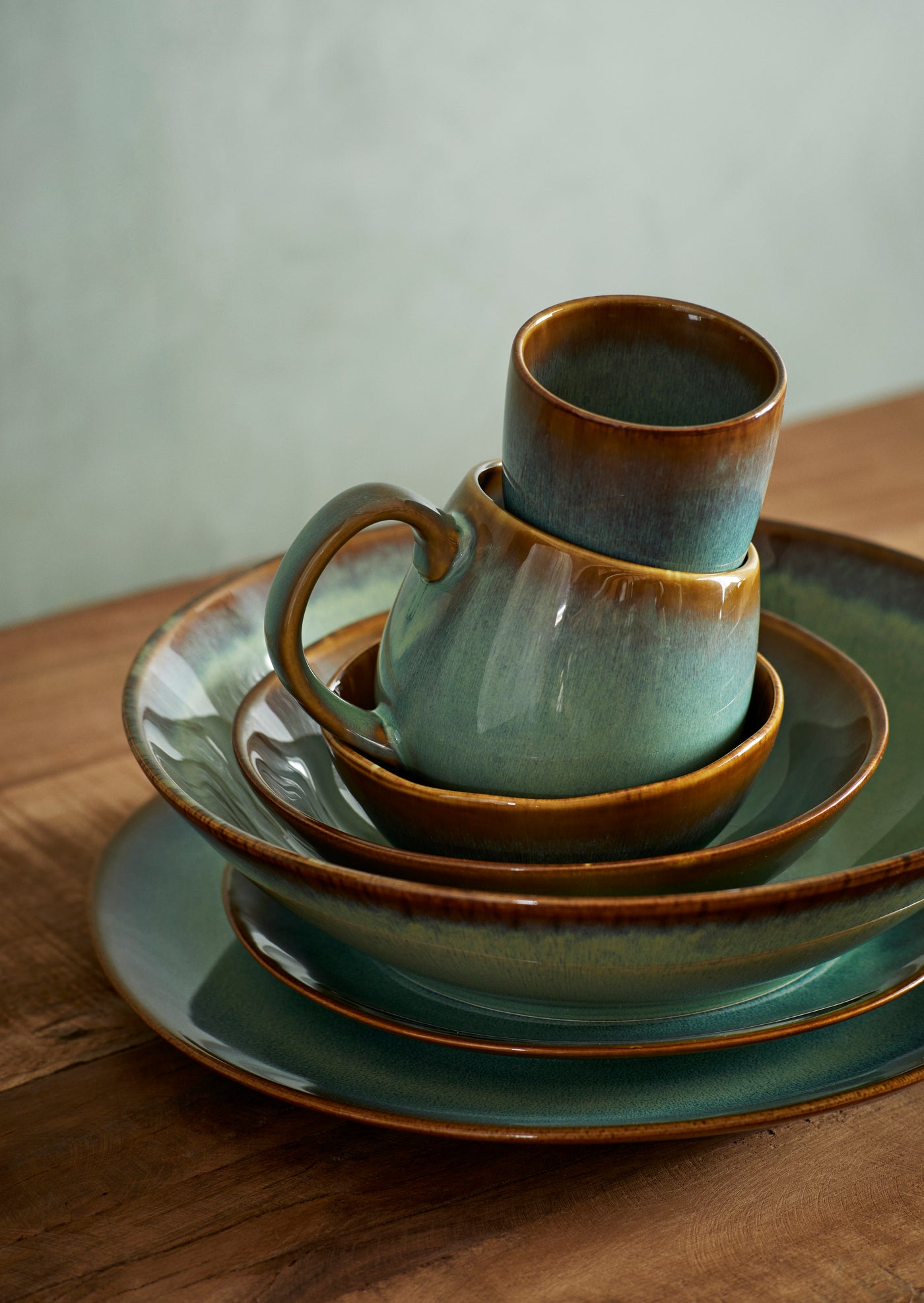 Stack of ceramic cups and saucers on a wooden surface with a neutral background