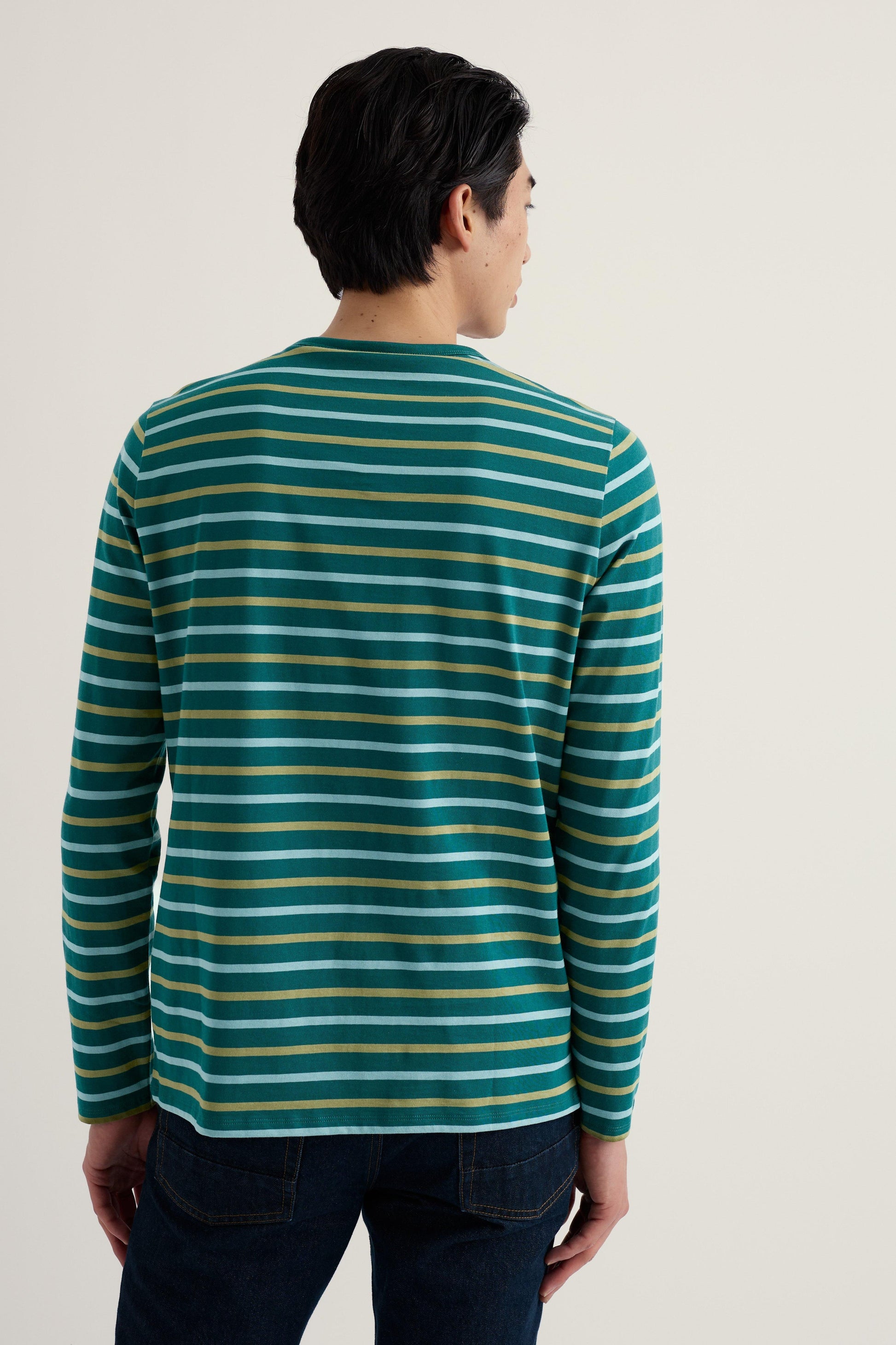 Man wearing a green and gold striped long-sleeve shirt against a plain background