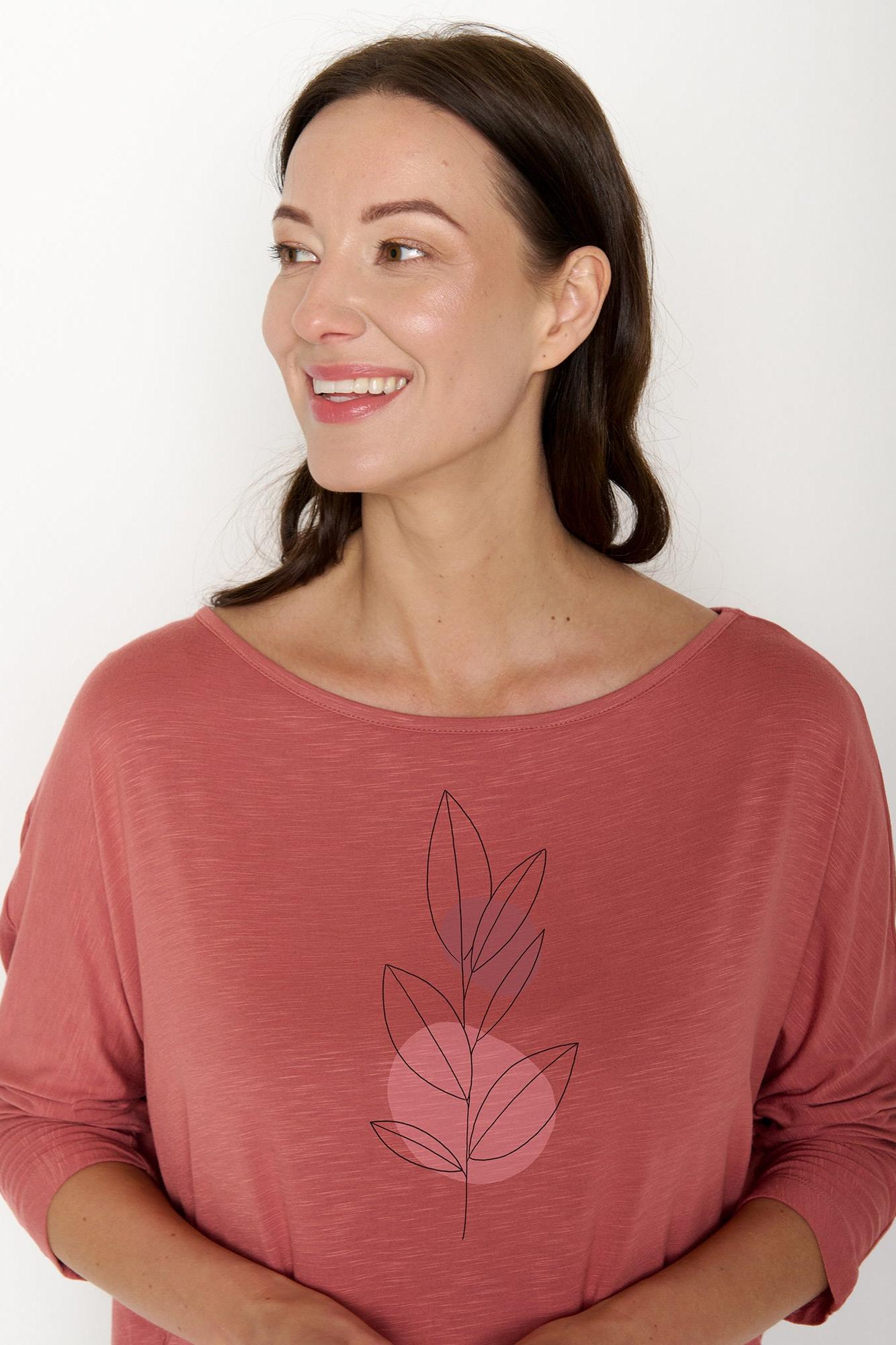 Woman wearing a pink long-sleeved shirt with a leaf design on a white background