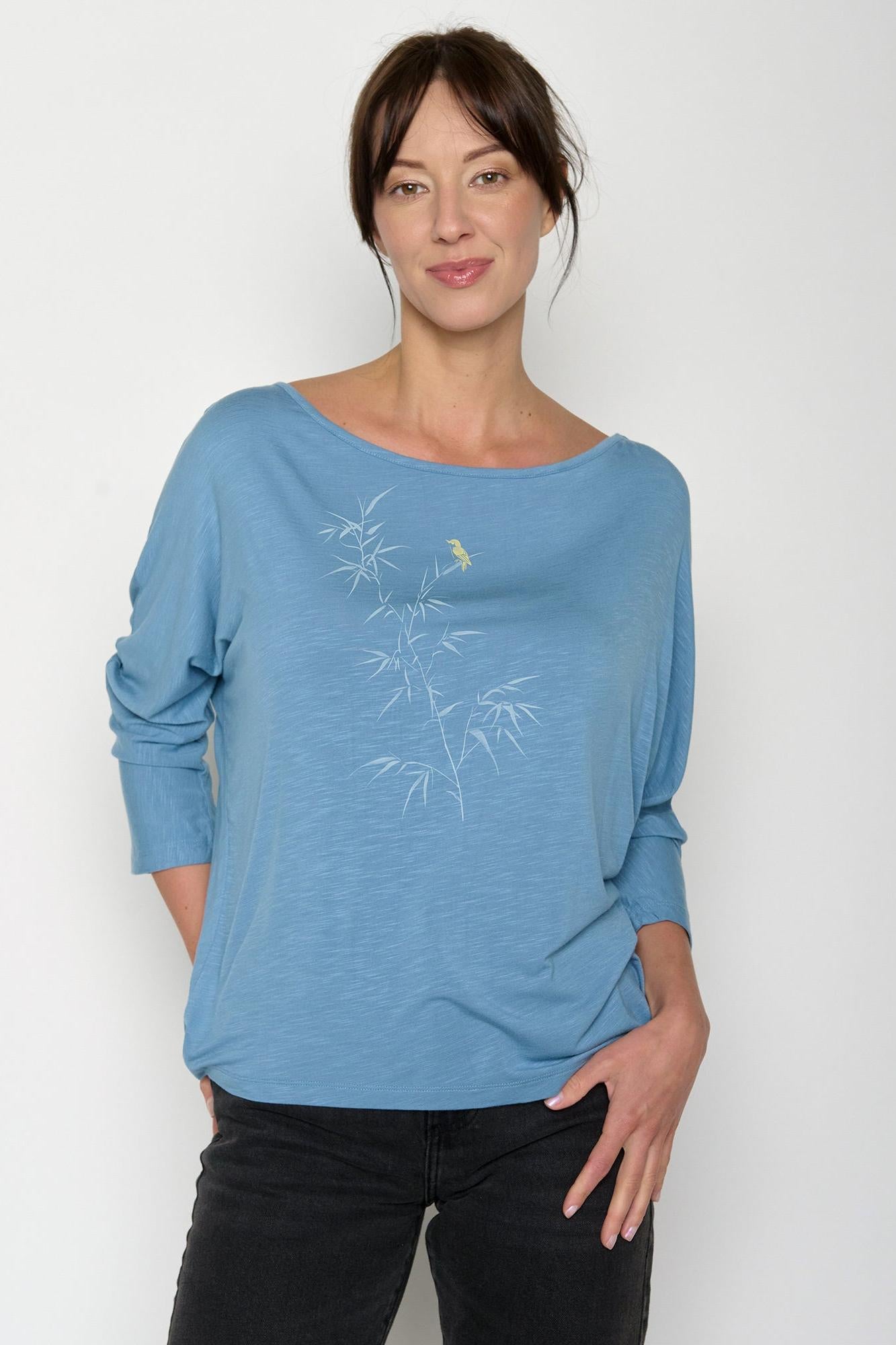 Woman wearing a blue eco-vero shirt with a subtle design on a white background