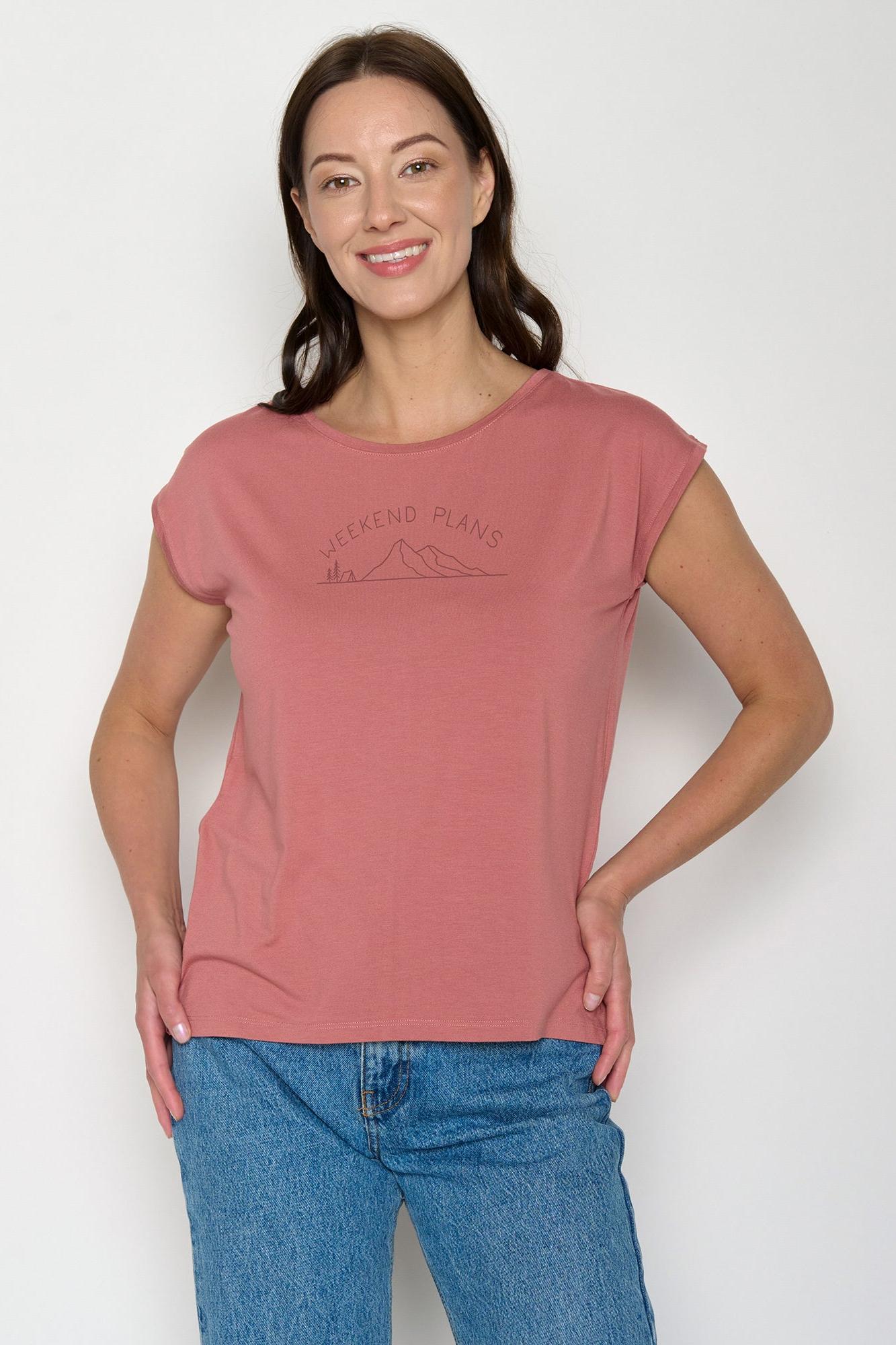 Woman wearing a pink eco-vero t-shirt with text 'weekend plans' on a white background