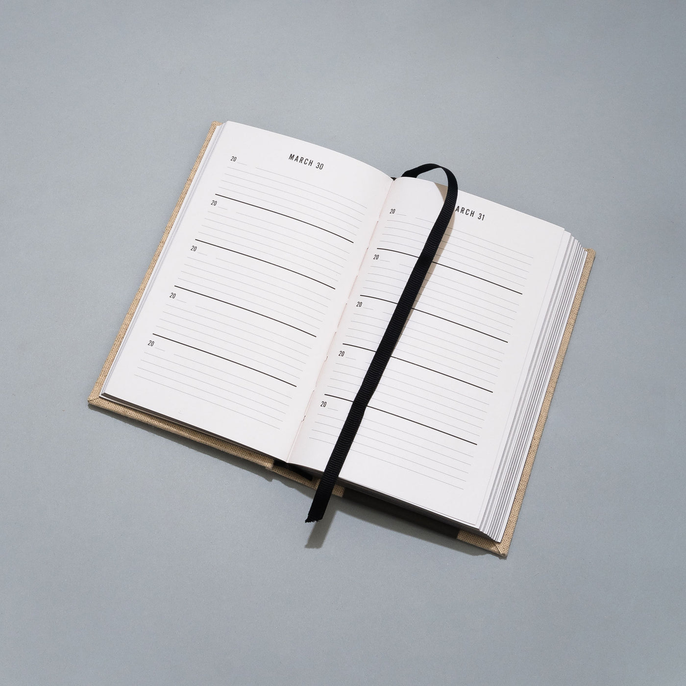 Open planner with a black strap on a gray background