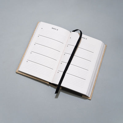 Open planner with a black strap on a gray background