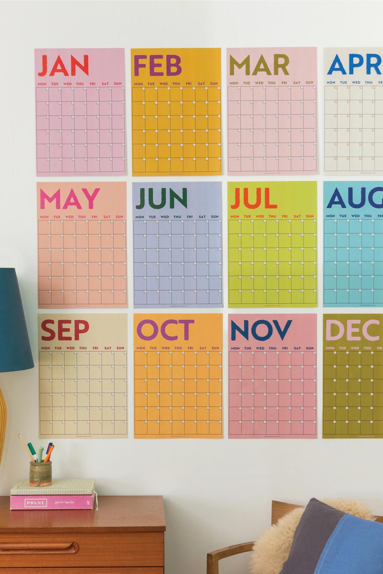 Colorful calendar wall art with months displayed on a white wall.
