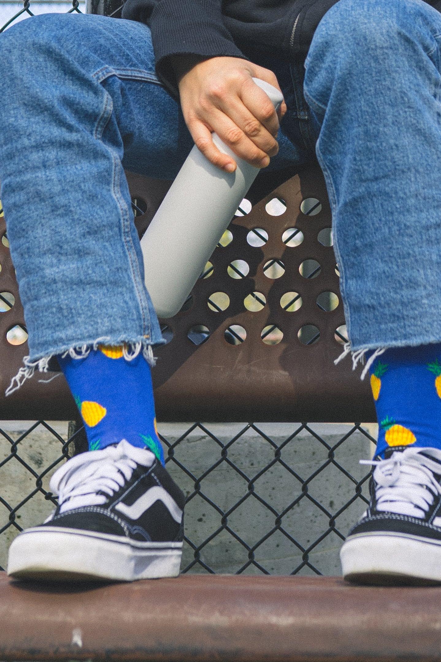Person wearing blue jeans and colorful bamboo socks sitting on a bench.