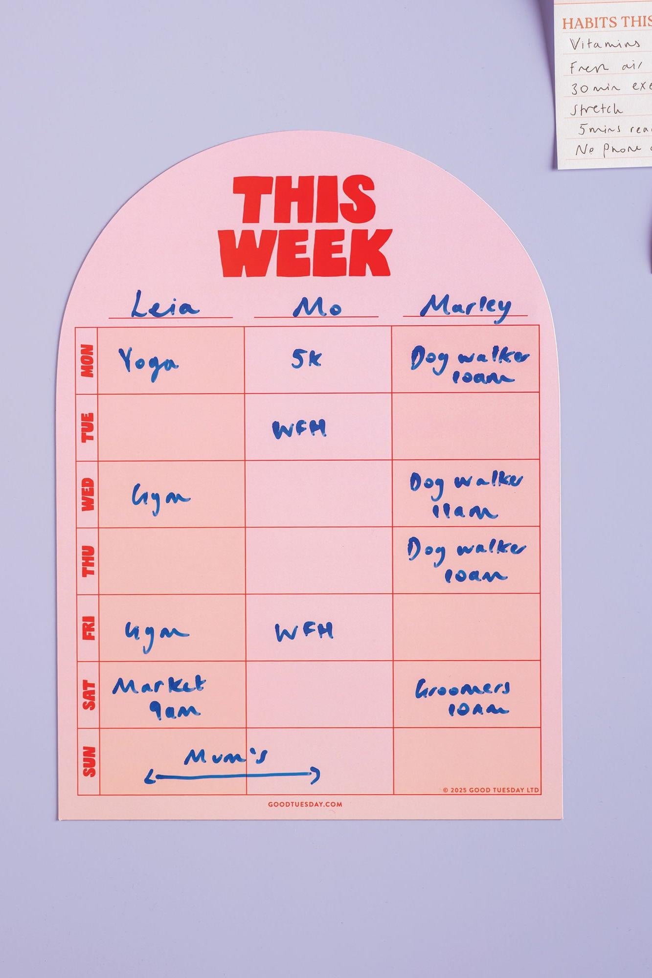 Weekly planner on a purple wall with handwritten tasks