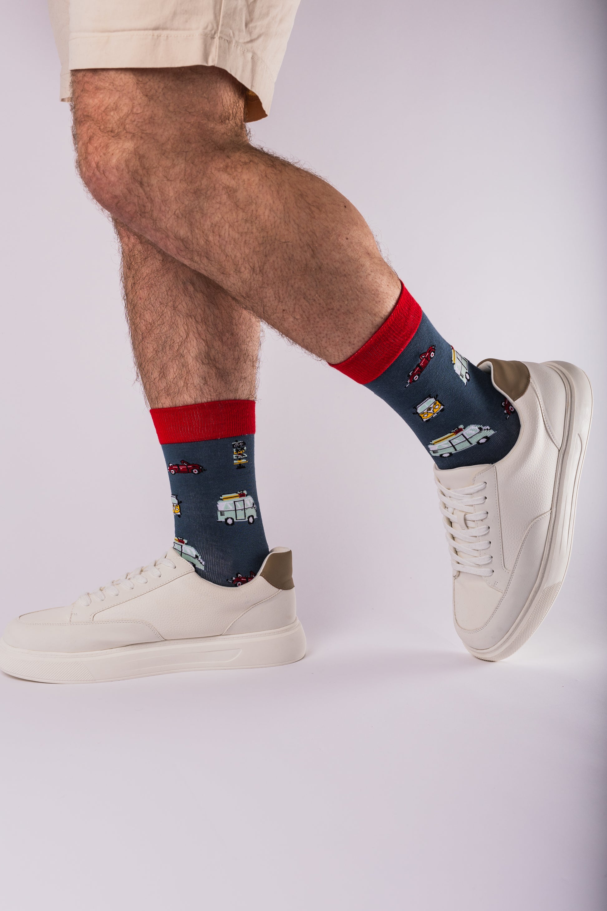 Person wearing navy and red socks with a design, paired with white sneakers on a light gray background