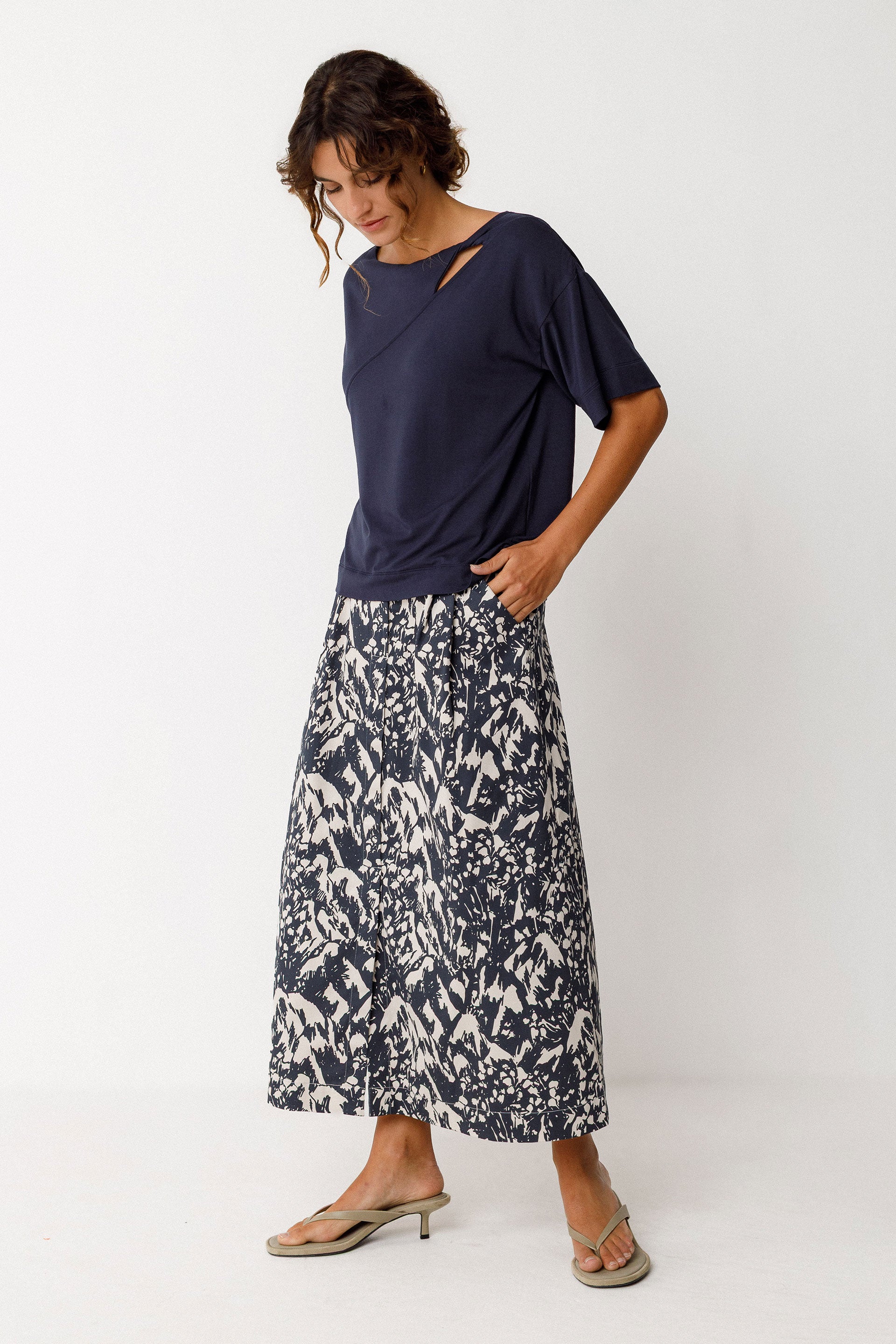 Woman wearing a navy top and patterned skirt on a white background