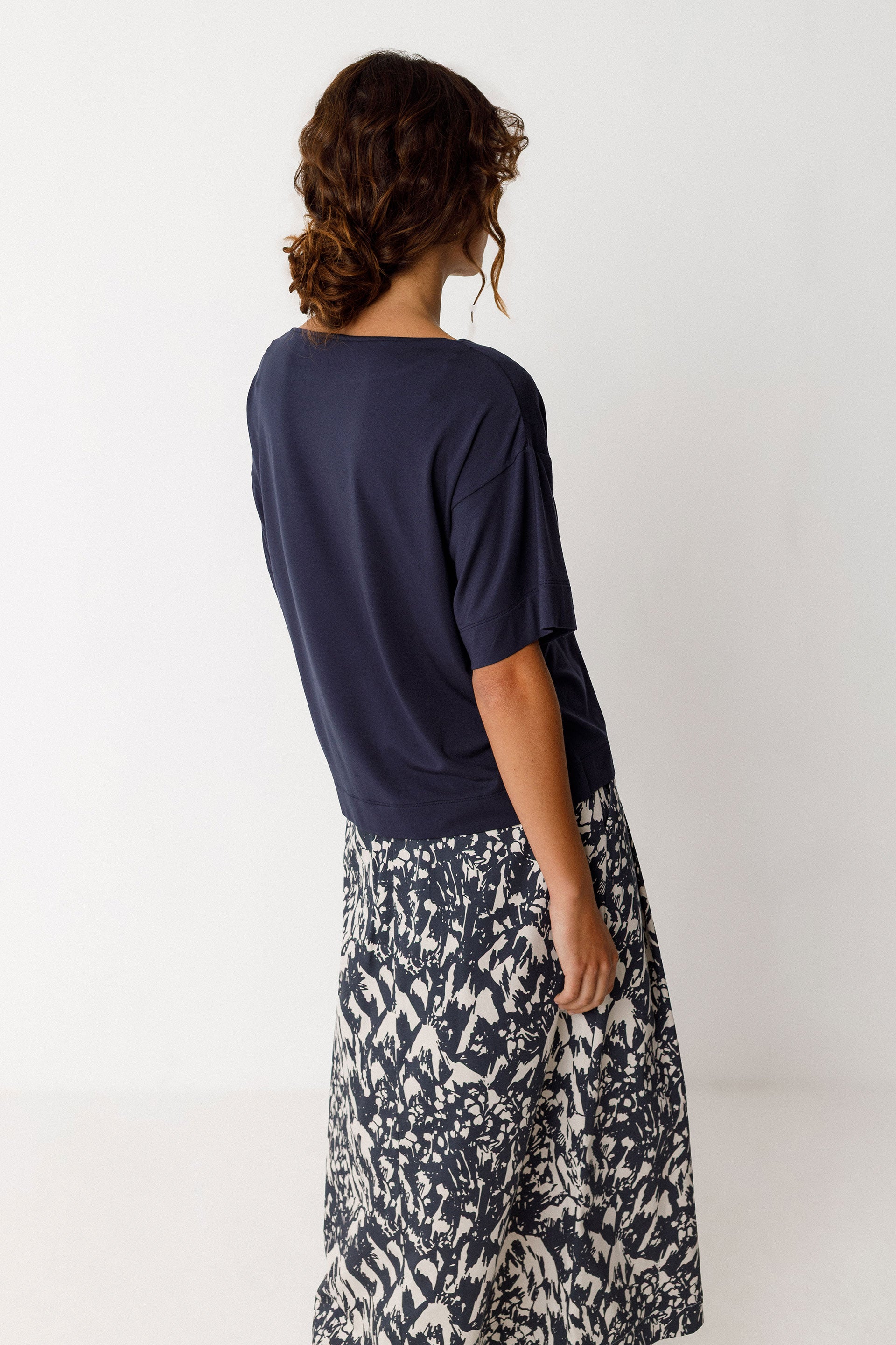 Model wearing a loose-fitting top with a boat neck and short sleeves, featuring a wrapped effect at the front.