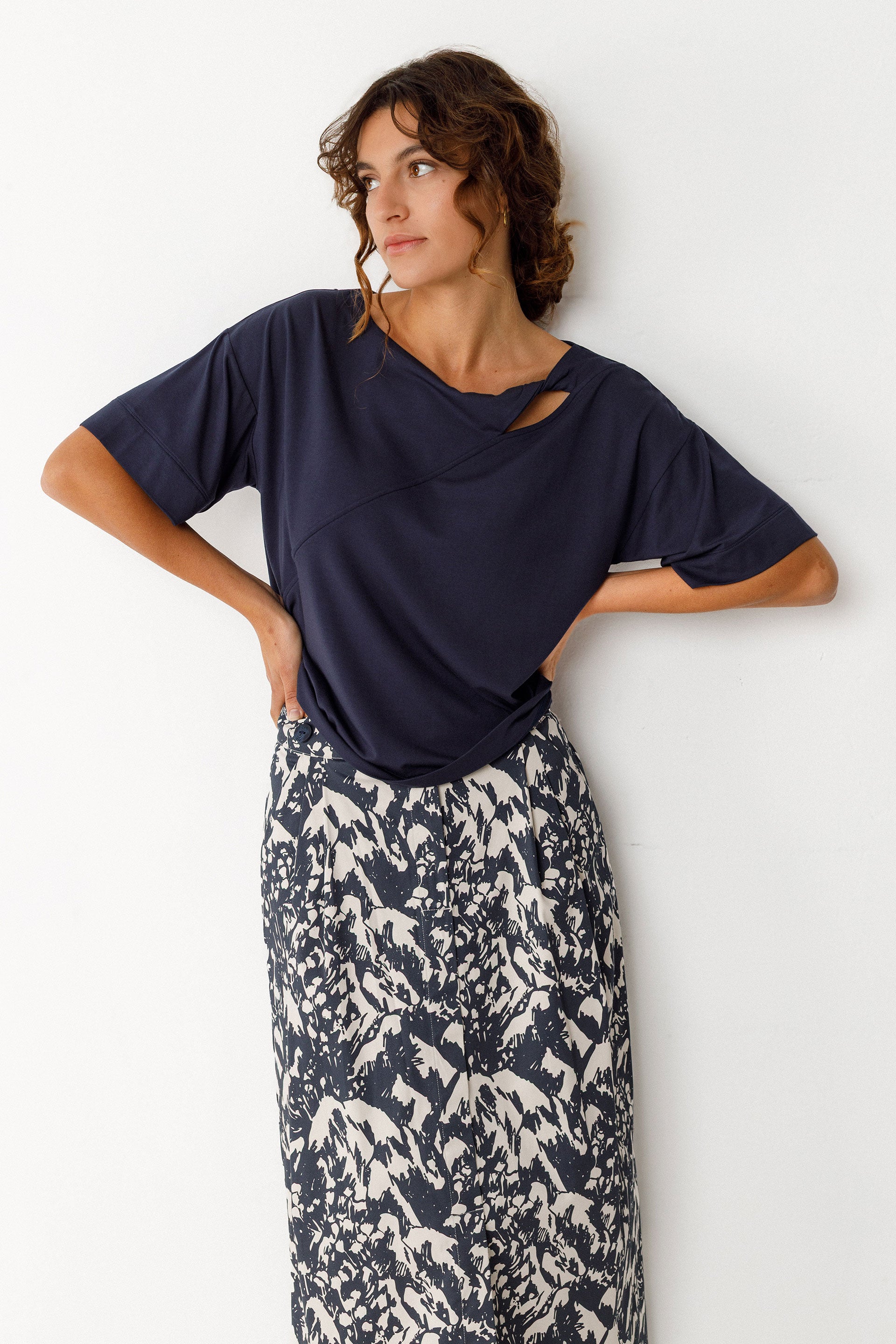 Model wearing an SKFK navy wrap top with printed skirt