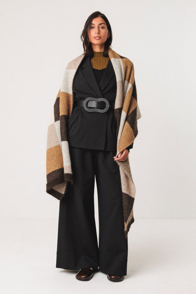 Woman wearing a black outfit with a patterned wool shawl on a white background