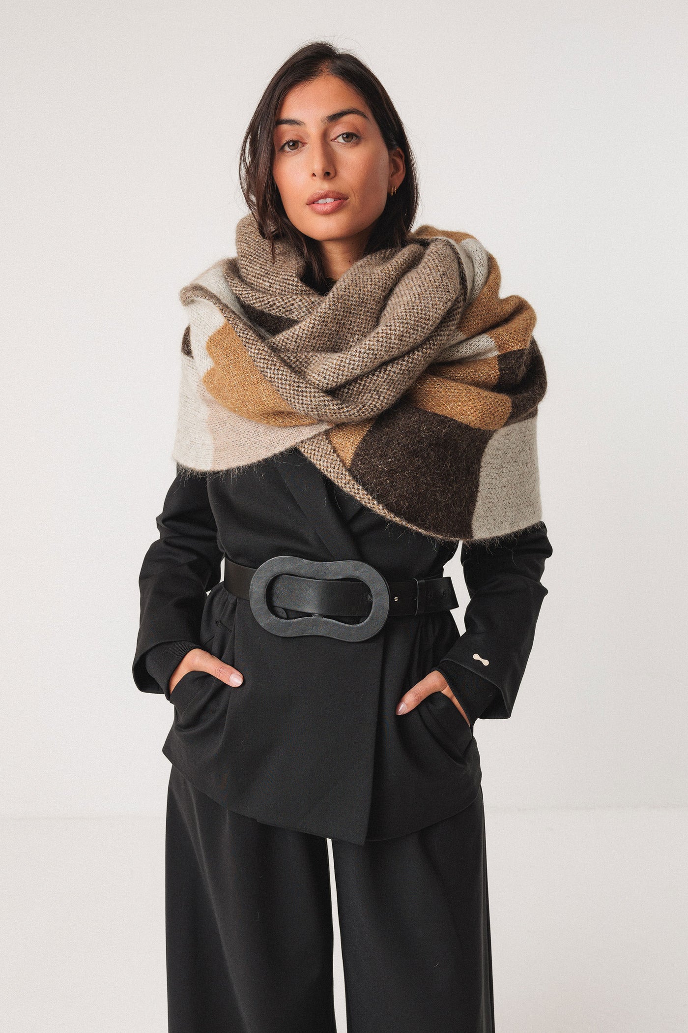 Woman wearing a patterned wool scarf and black outfit on a white background