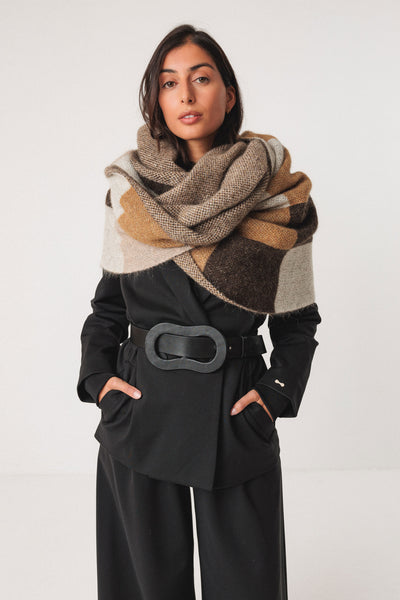 Woman wearing a patterned wool scarf and black outfit on a white background