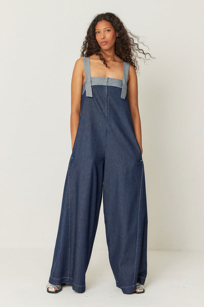 long, relaxed-fit denim jumpsuit featuring front pockets, decorative stitching, and a zip closure