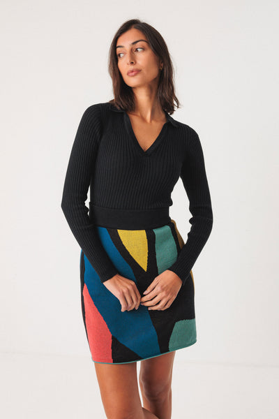 Woman wearing colourful organic cotton skirt with black knit top on white background