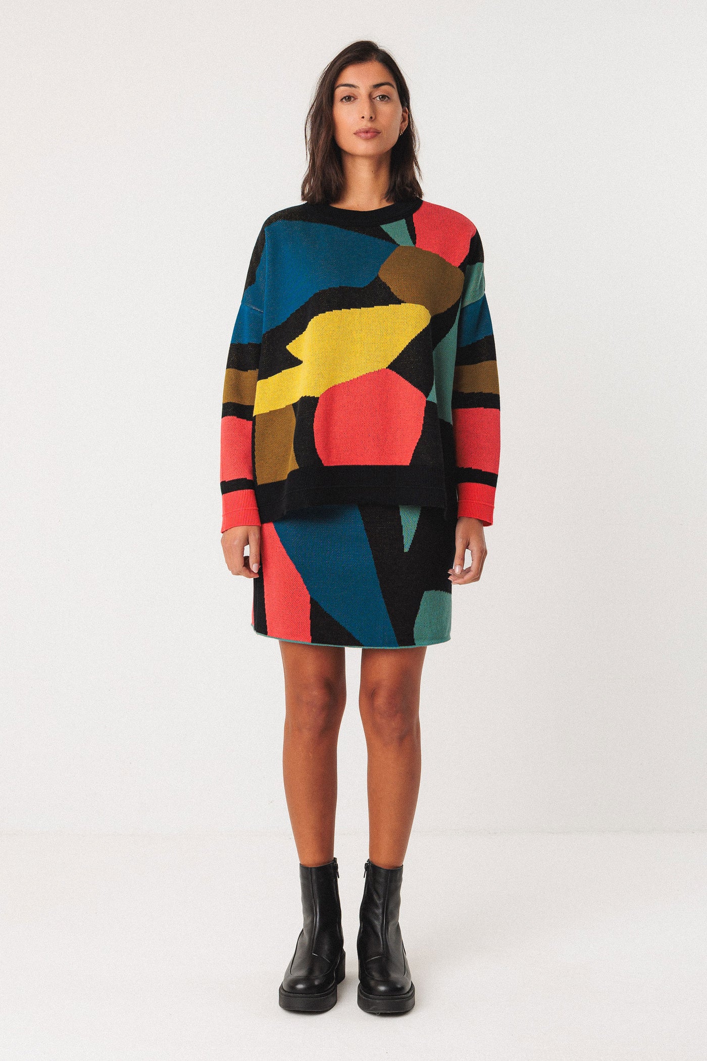 Woman wearing a colourful organic cotton sweater and skirt set on a white background