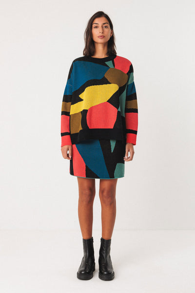 Woman wearing a colourful organic cotton sweater and skirt set on a white background