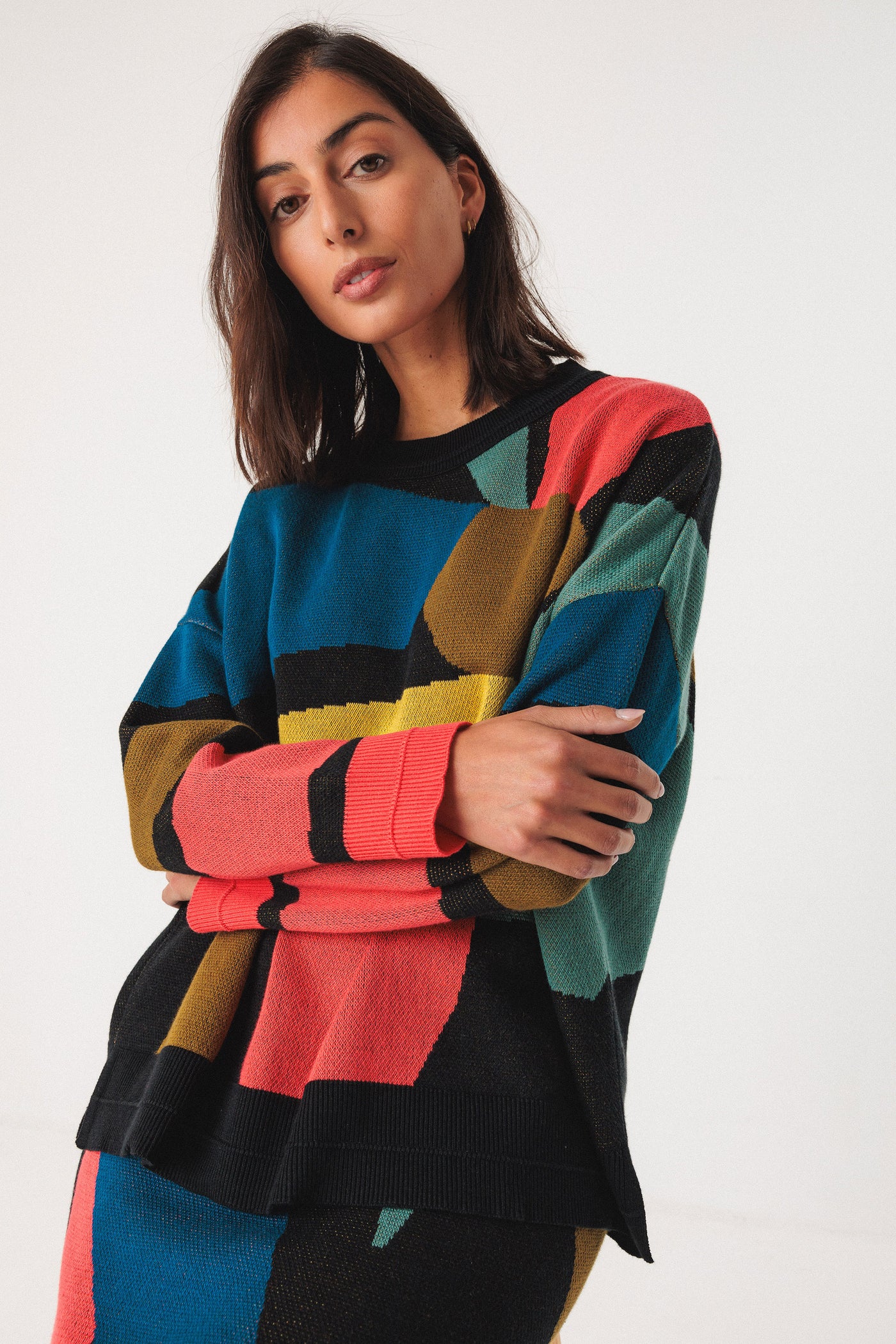 Woman wearing a colourful organic cotton sweater with geometric pattern on a white background