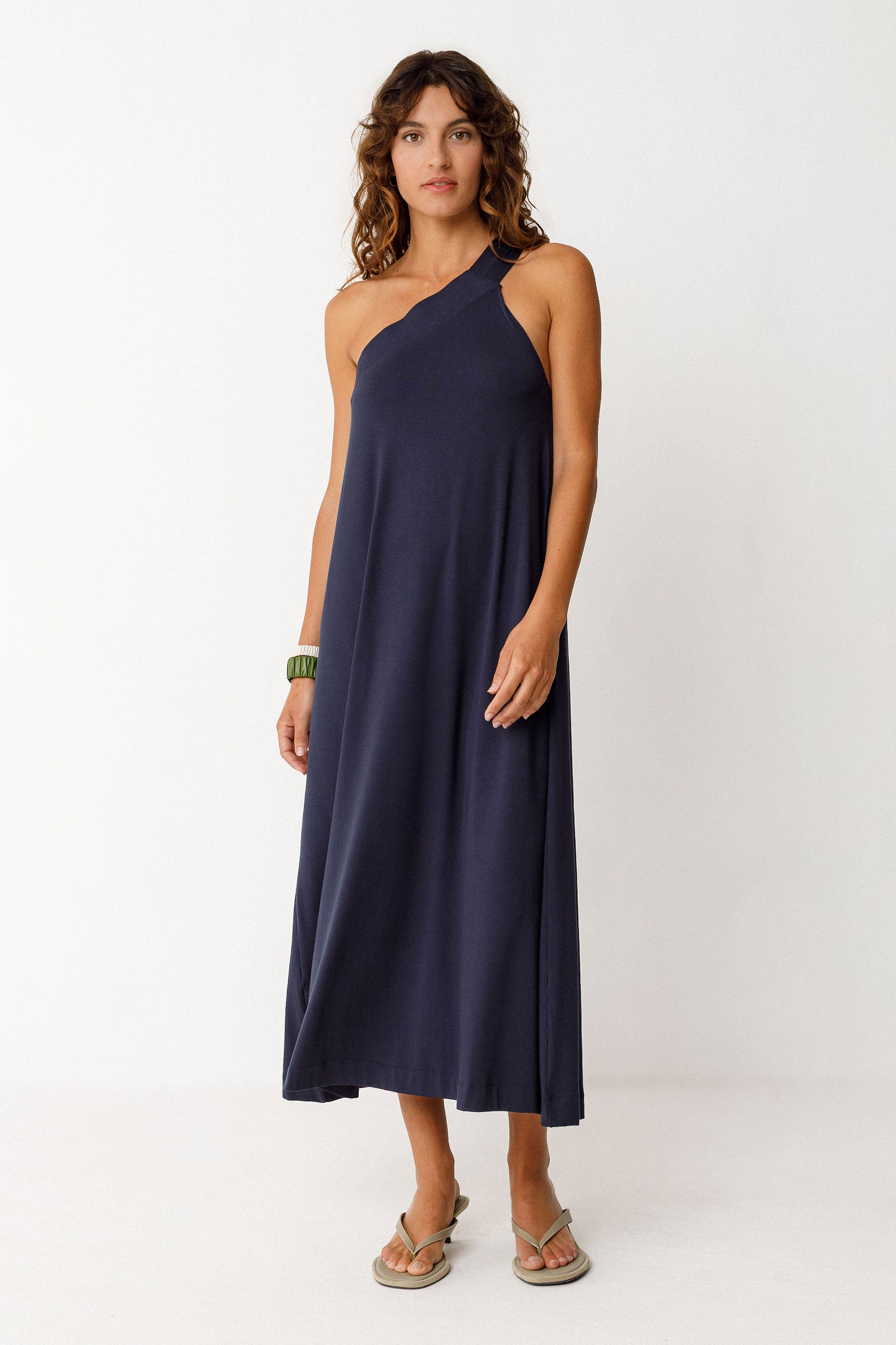 Woman wearing a navy blue one-shoulder dress on a white background