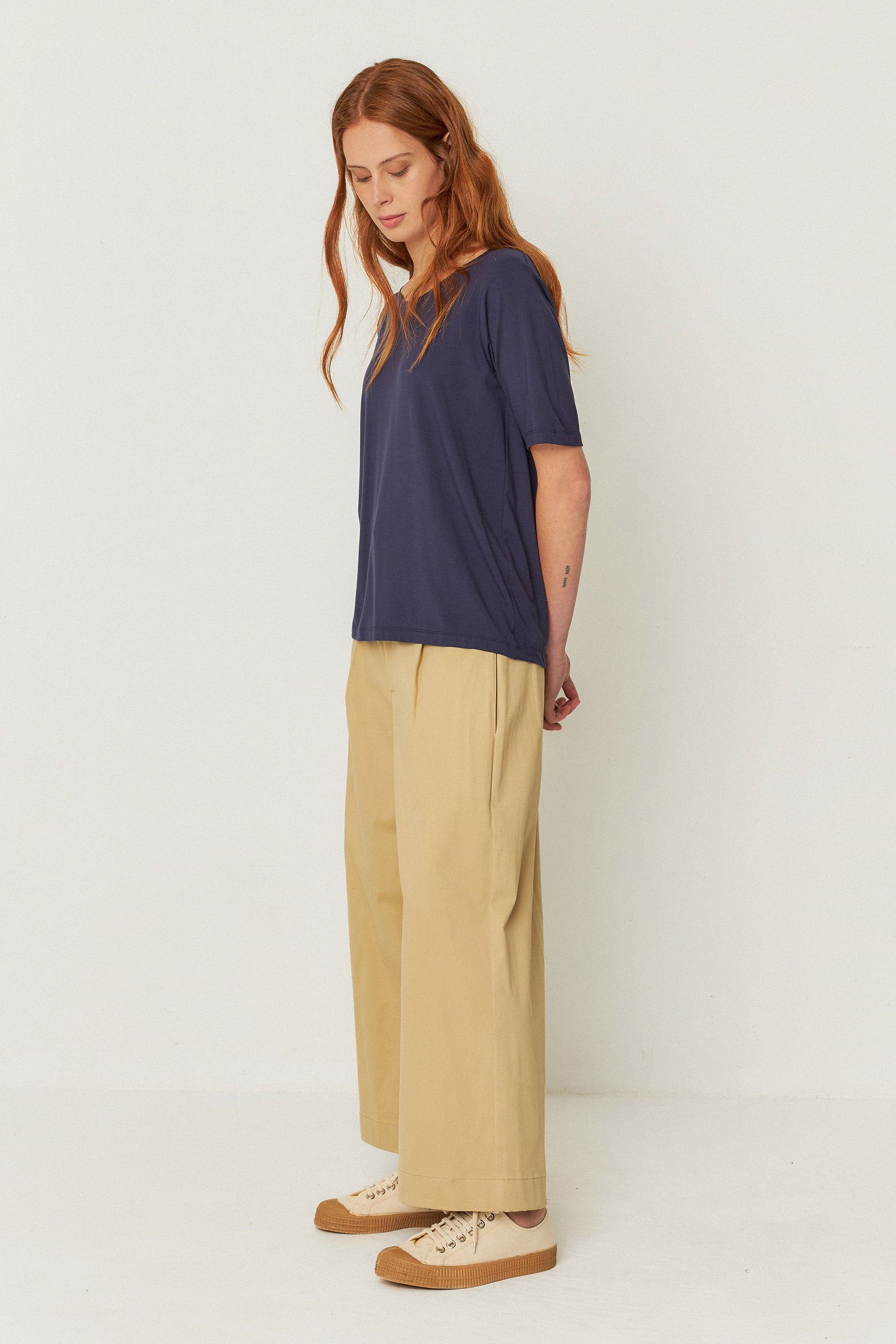 A side profile of the model, showing the length of the t-shirt and paired with cream culottes.