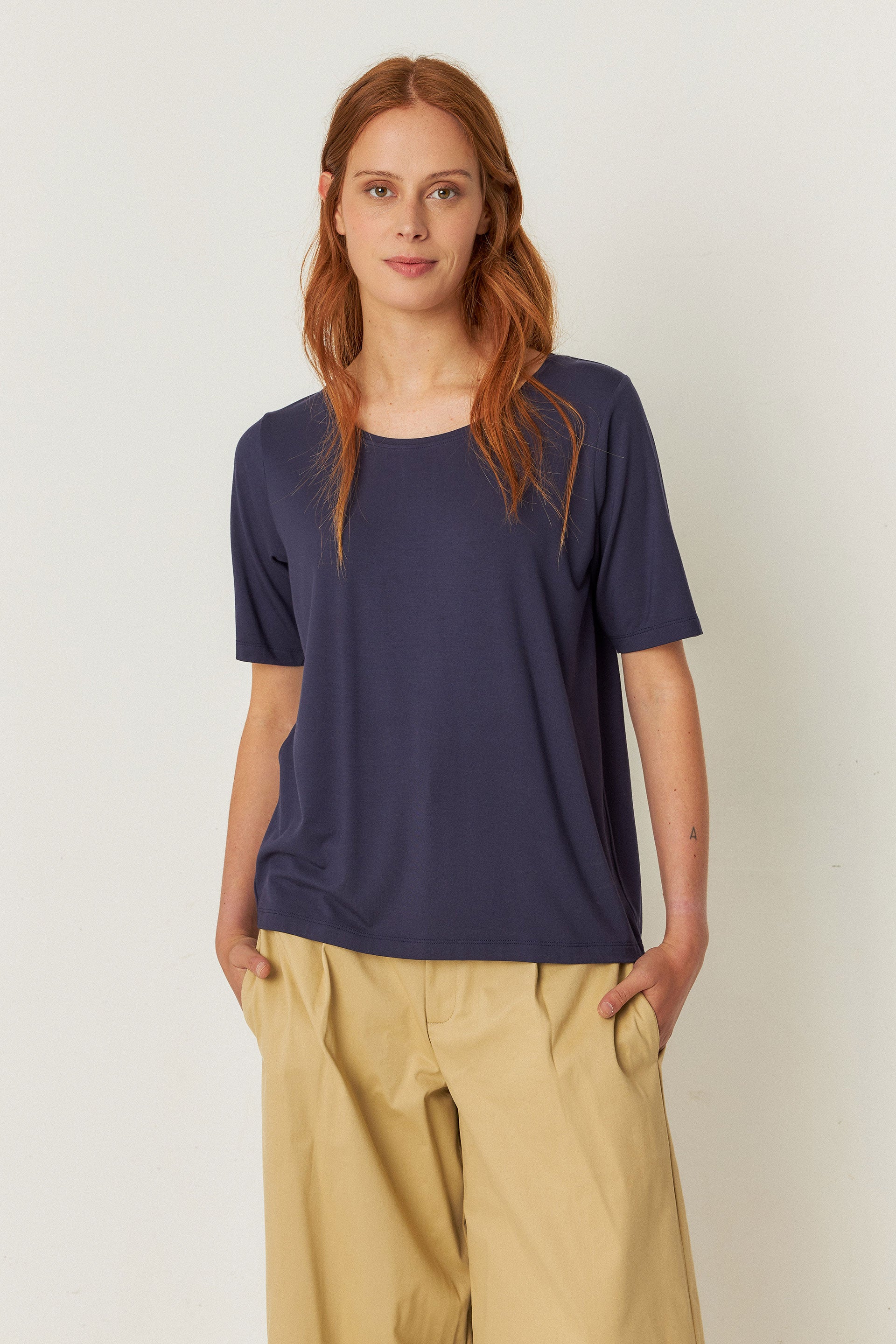  A woman wearing a loose-fitting top with a boat neckline and 3/4-length sleeves.