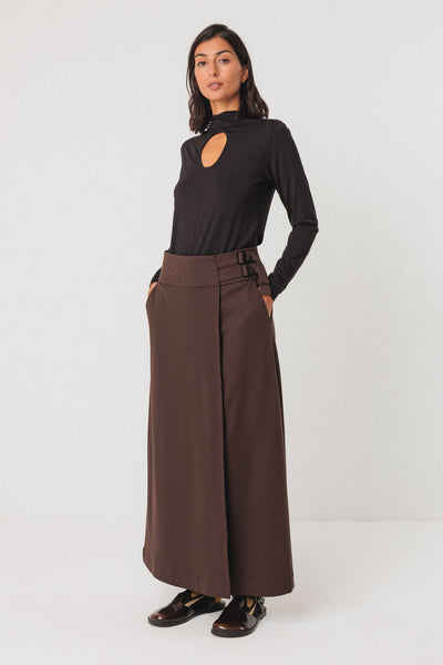 Woman wearing a black long-sleeve tencel top and brown wide-leg pants on a white background
