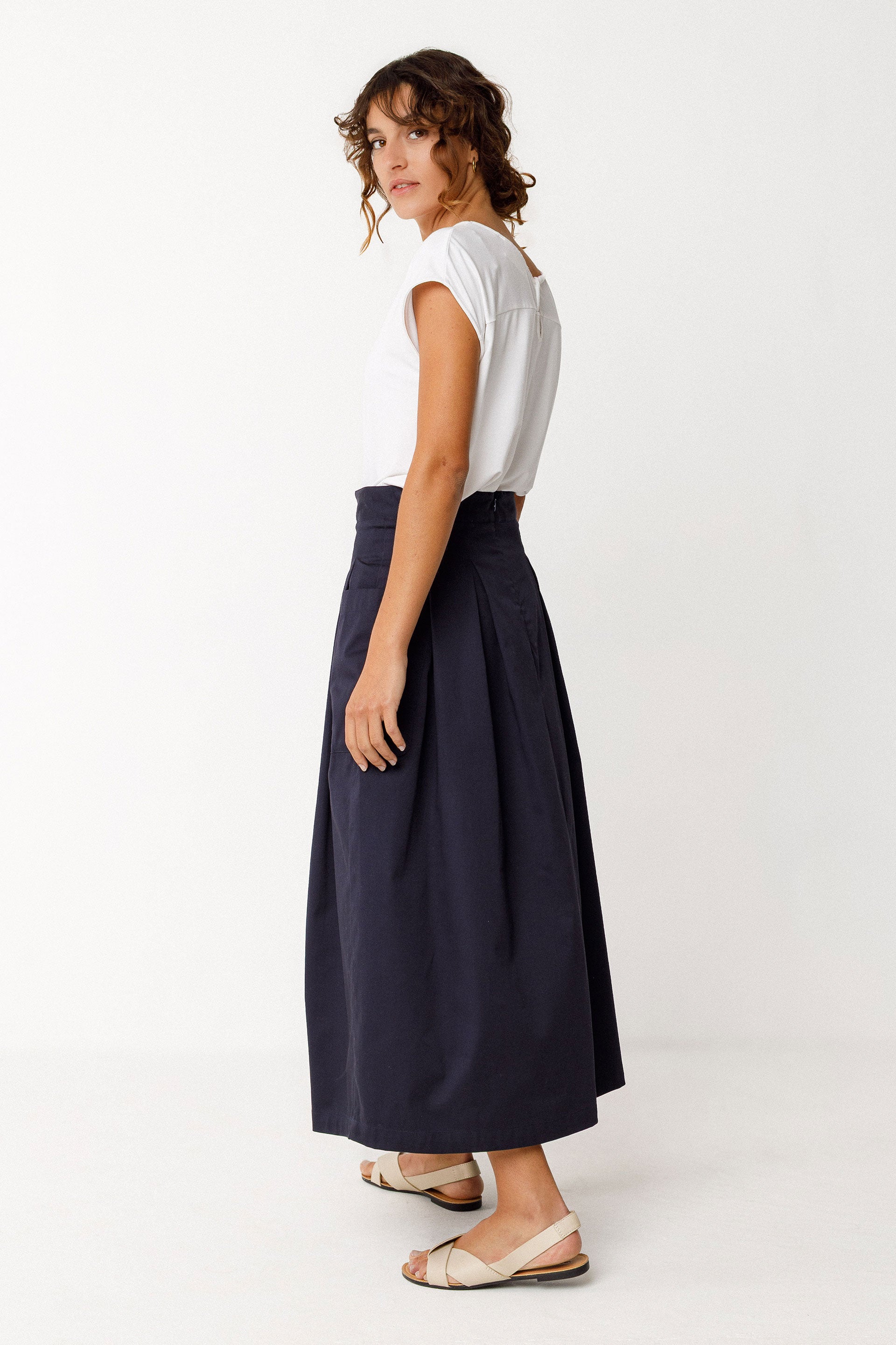 Woman wearing a white Tencel top and navy skirt on a white background
