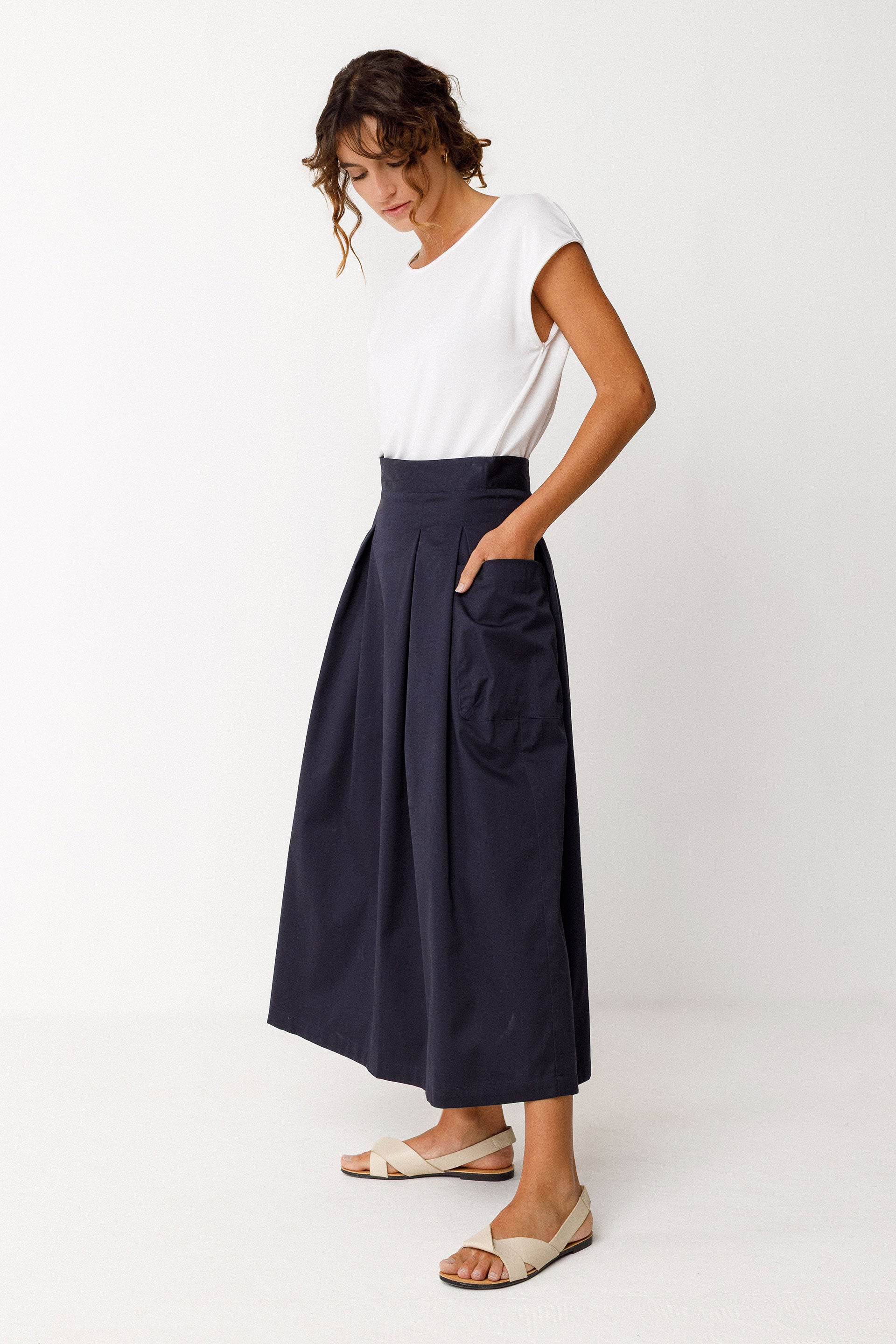 Woman wearing a white top and navy blue skirt on a white background