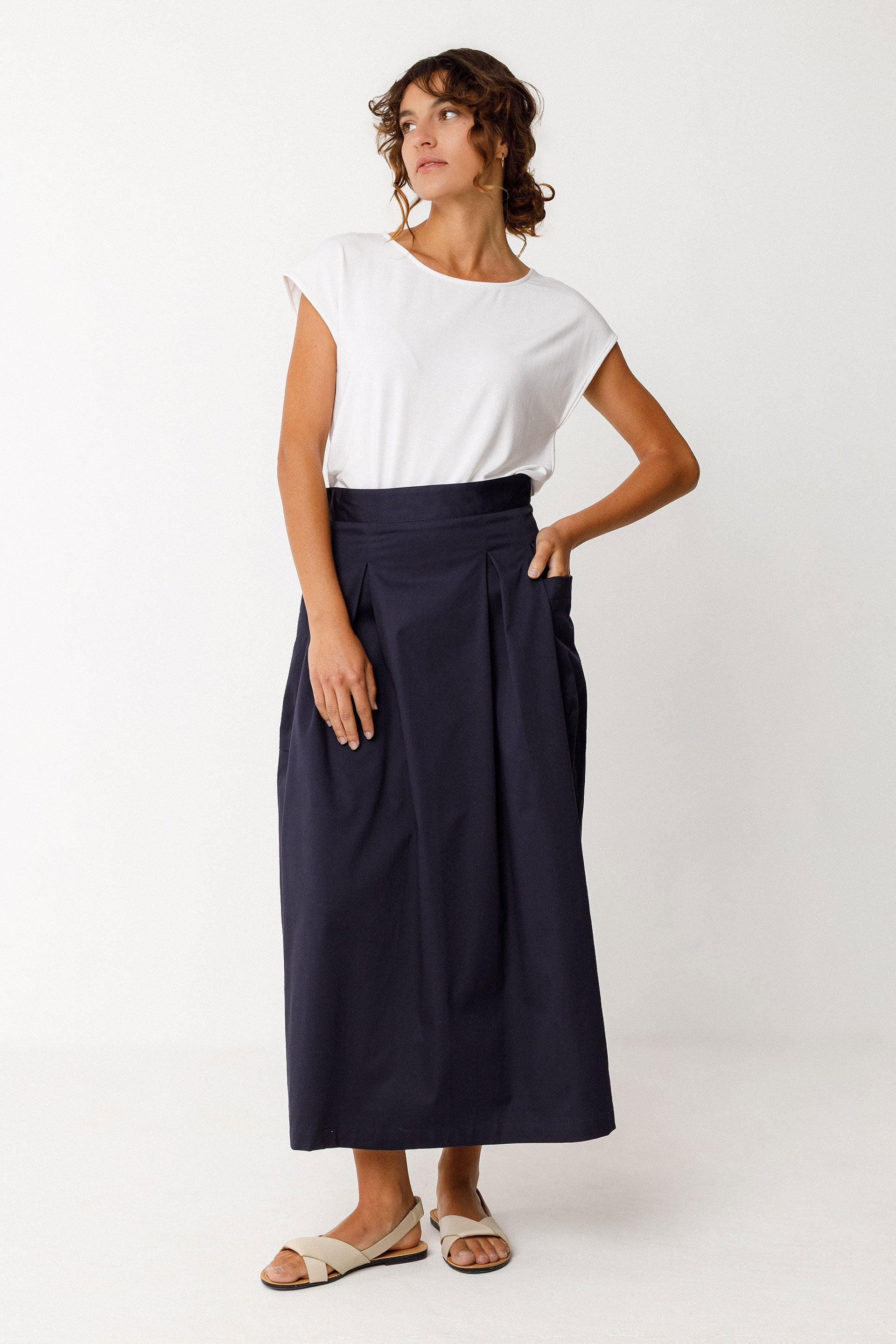 Woman wearing a round neck top with short sleeves and navy skirt on a white background